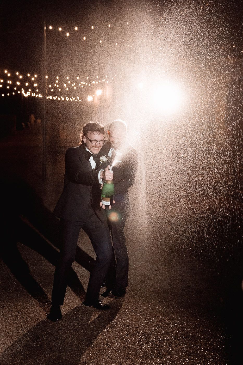Dancing in the rain and string lights creates magical silhouettes during a nighttime celebration.