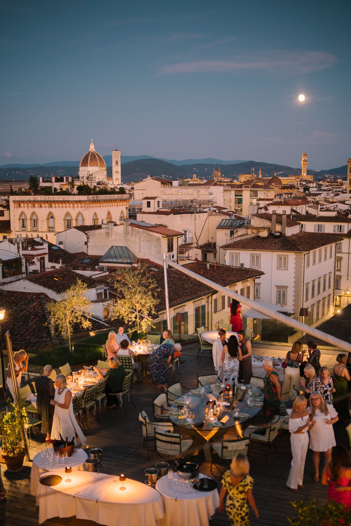 A scenic view of the city of Florence, Italy at night, with the Duomo and other historic buildings illuminated under a moonlit sky.