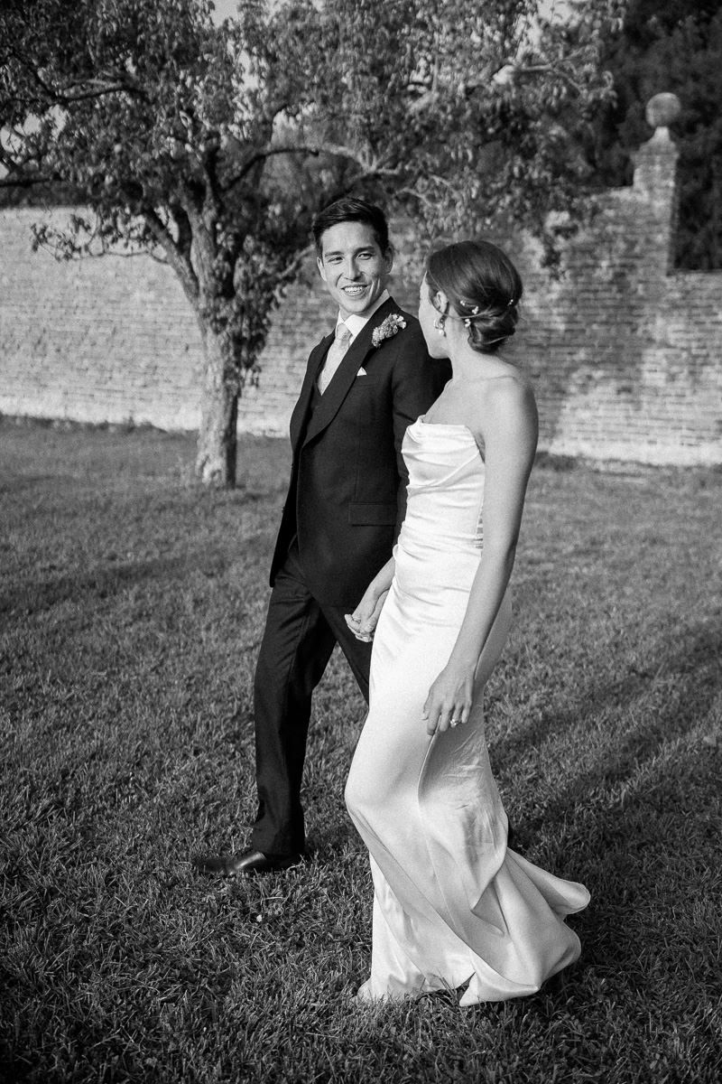 A romantic black and white wedding photo sequence showing a couple walking together on a grassy lawn.