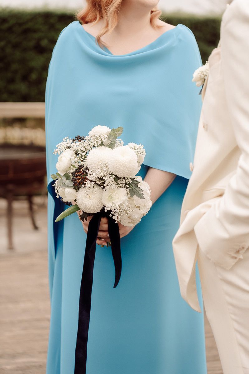 Close-up of a light blue bridesmaid dress with a white floral bouquet tied with black ribbon.
