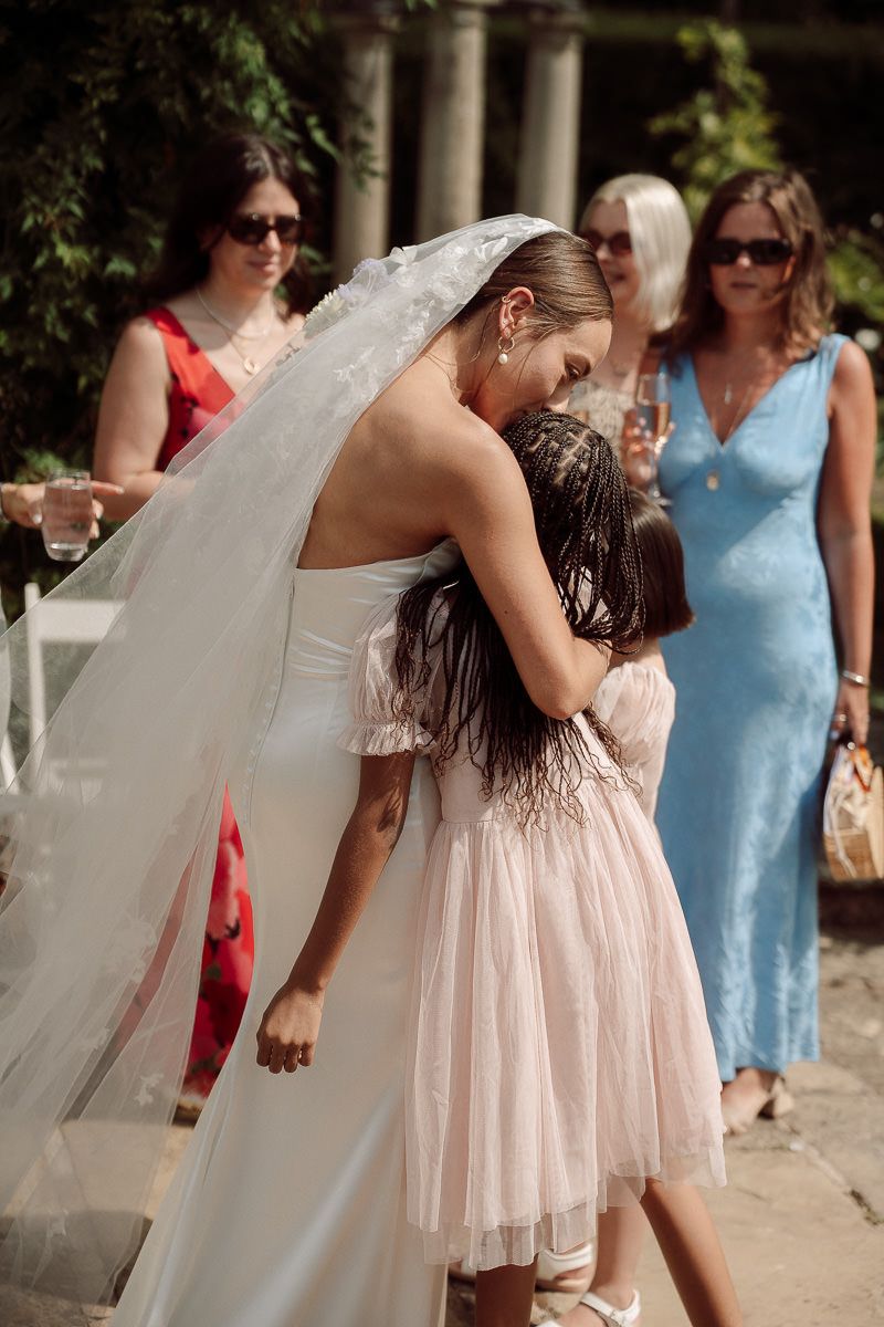 Wedding party walking outdoors with bride in white dress and bridesmaids in light colored dresses.