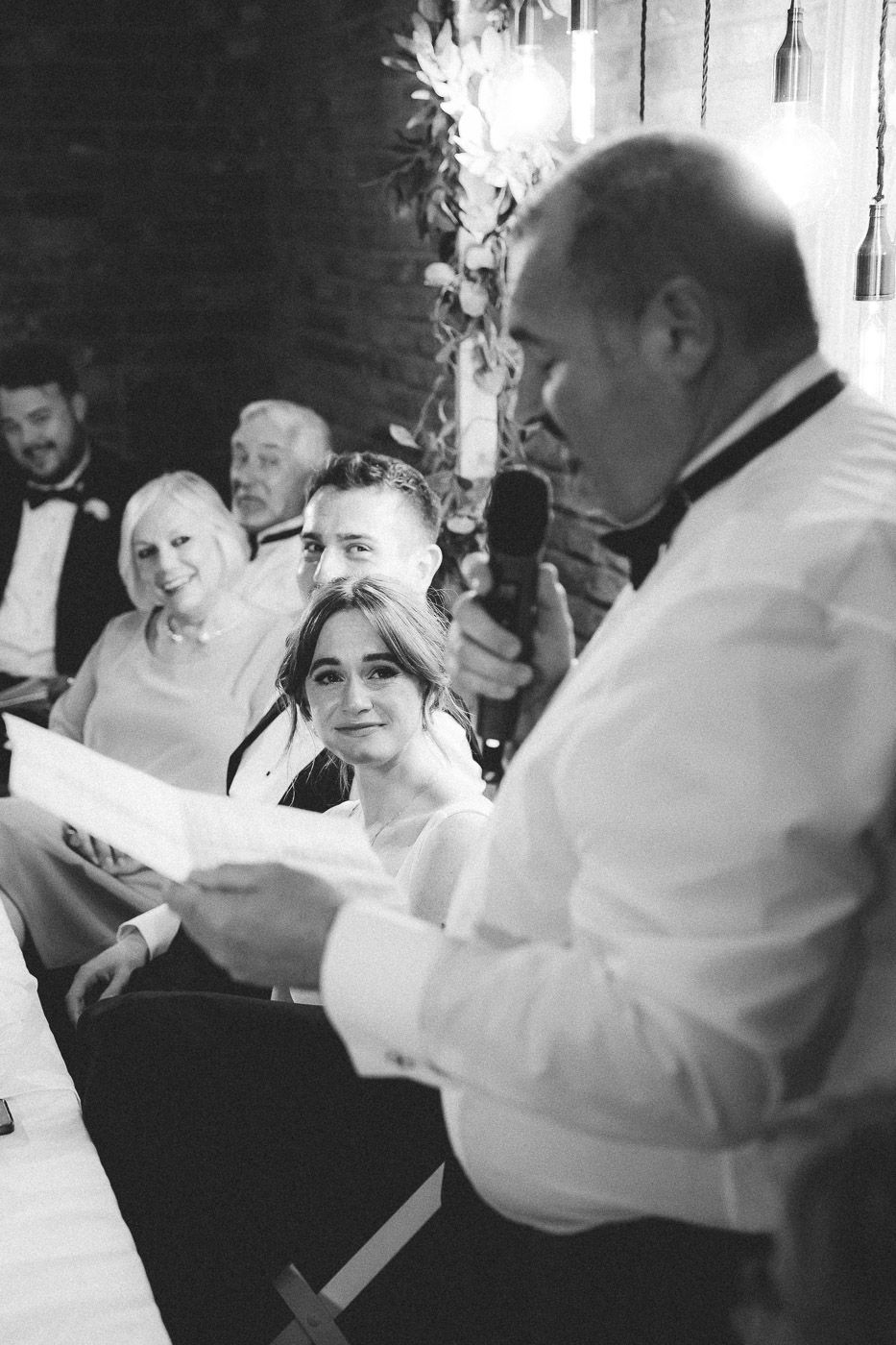 Black and white photo of guests dancing and celebrating at a lively wedding reception.