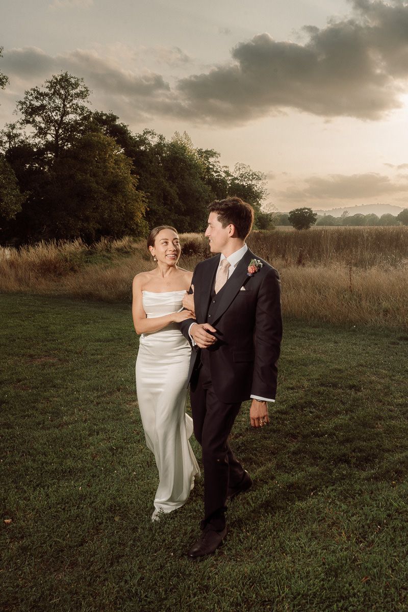 A couple in wedding attire shares an intimate moment in a golden field at sunset.