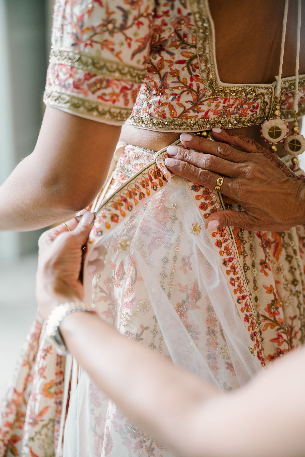 A close-up view of a woman's hands adjusting the lace details on a floral-patterned dress.