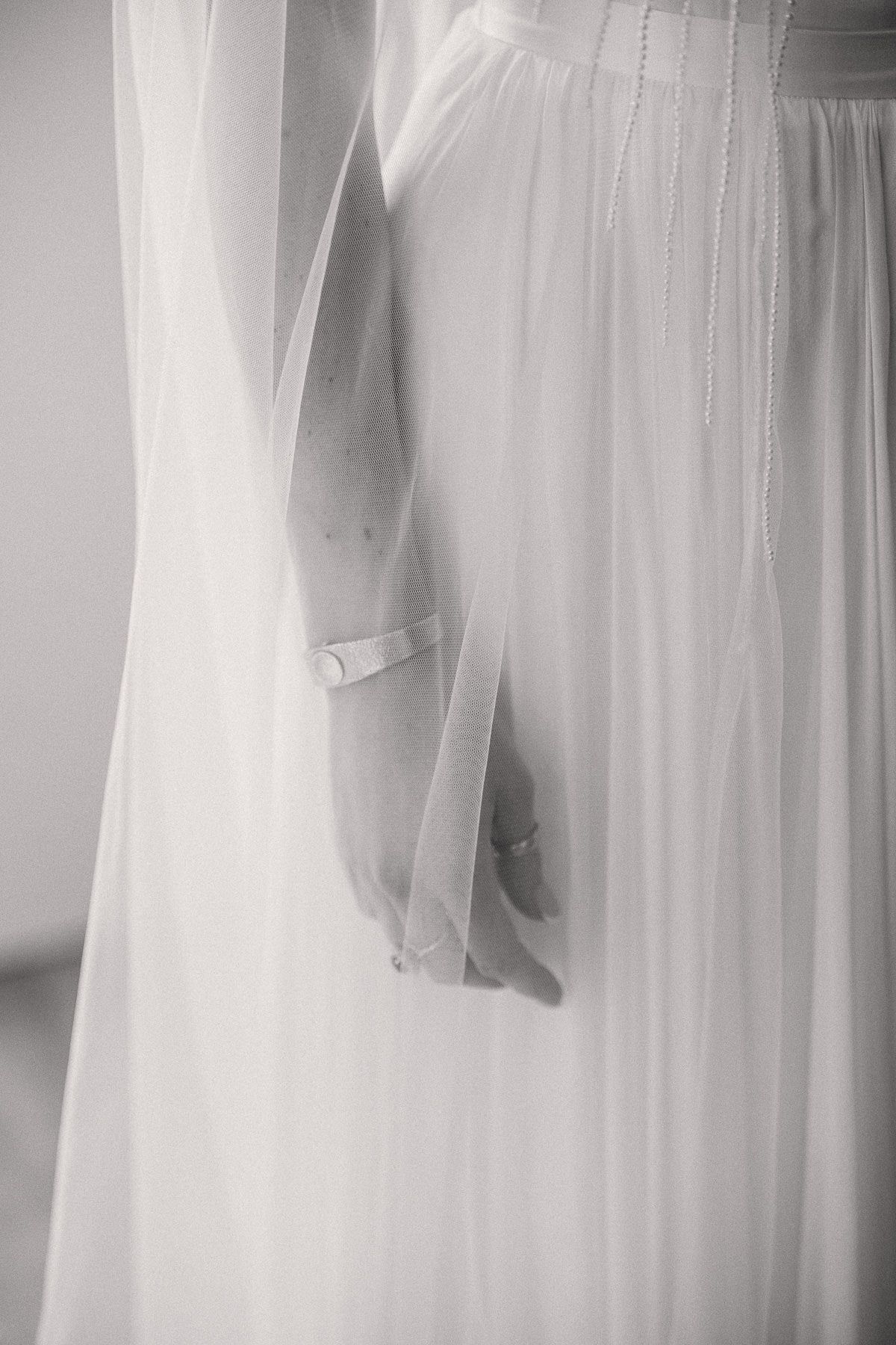A close-up view of a delicate, flowing white wedding dress with a veil attached.