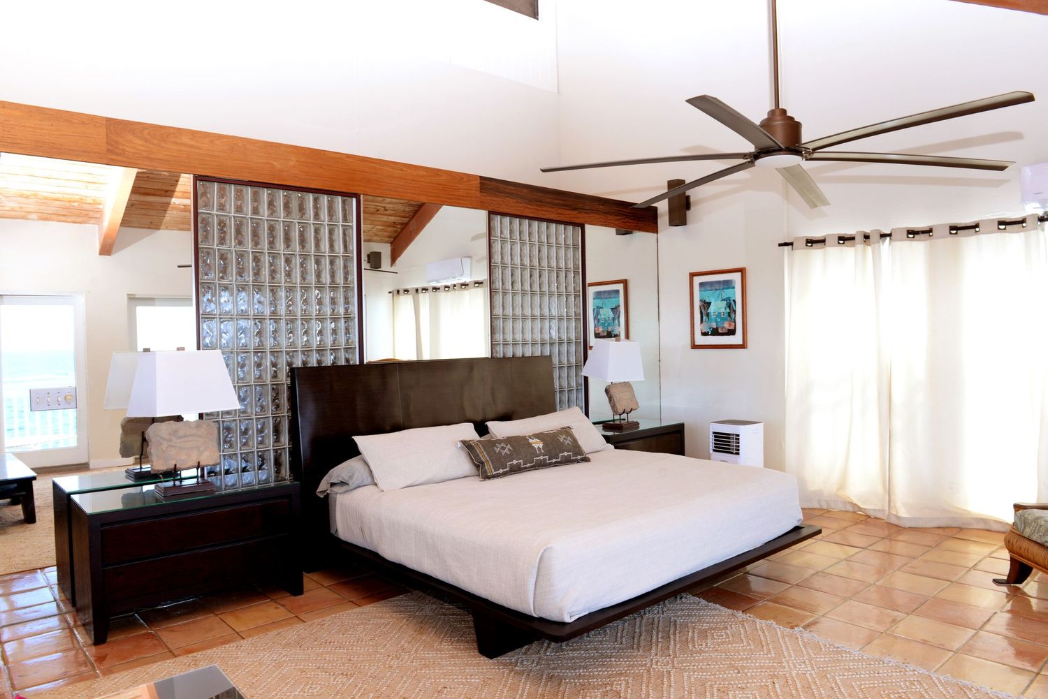 Spacious bedroom with wooden beams, ceiling fan and terrace doors.