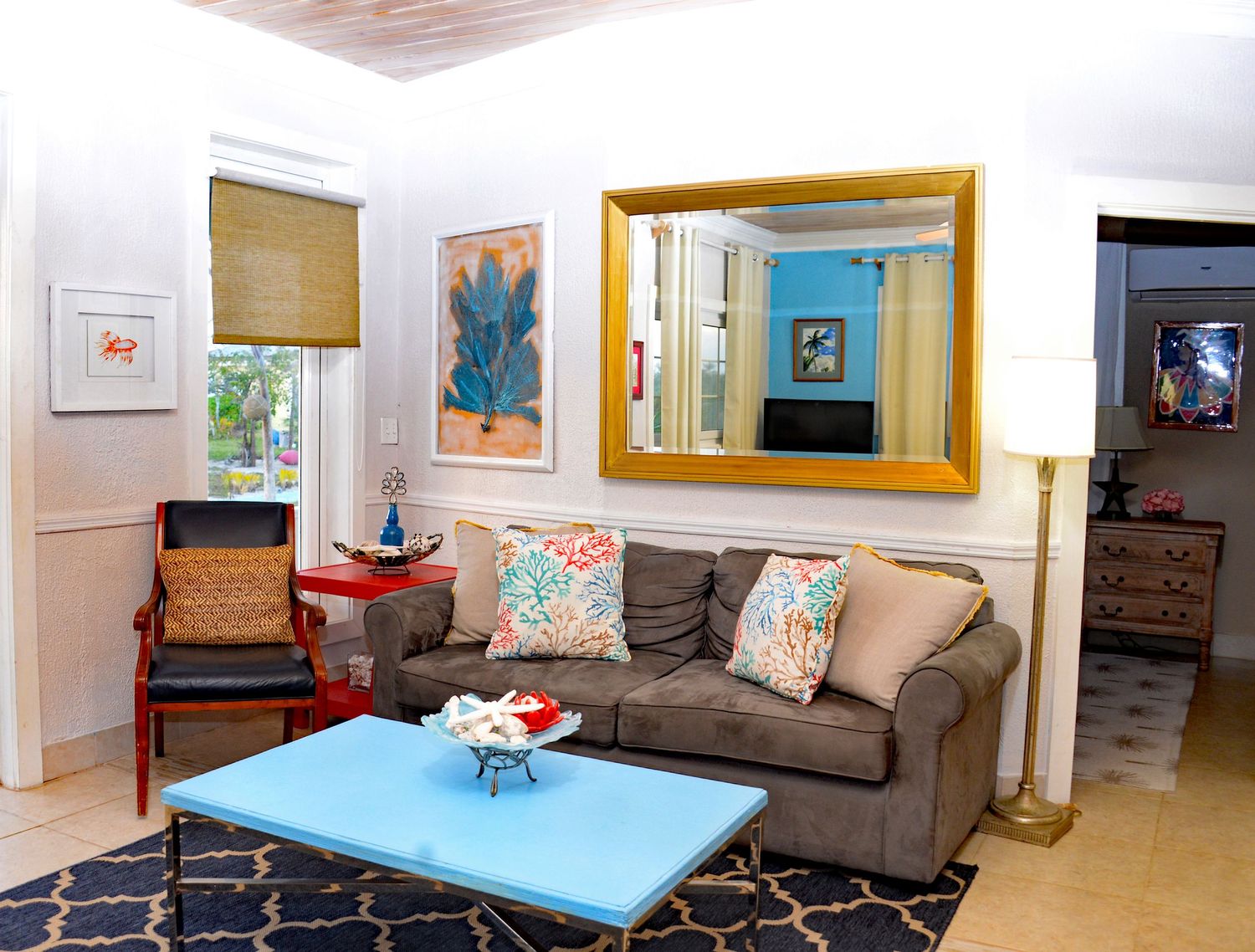 Cozy living room with brown sofa, blue coffee table and gold framed mirror.