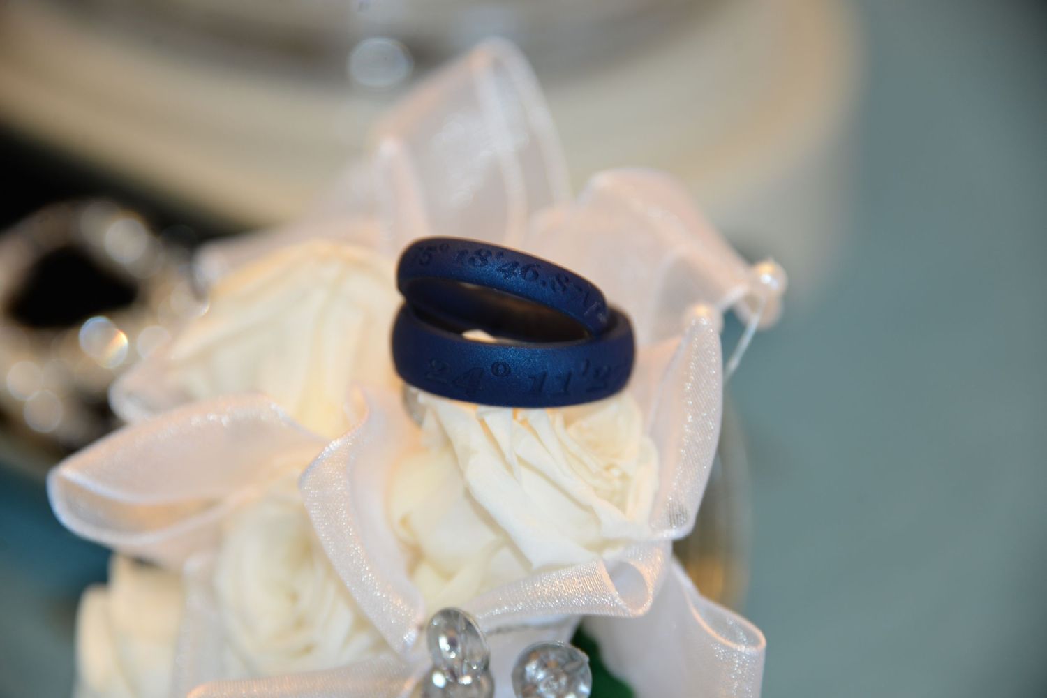 Navy blue wedding rings displayed on white fabric with soft focus background.