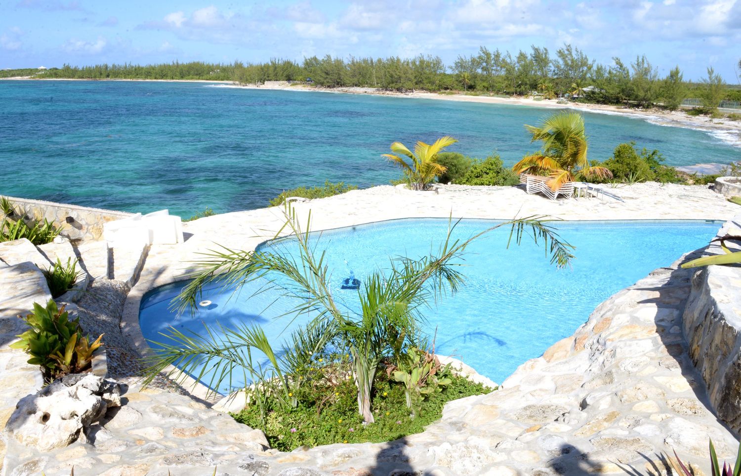 Infinity pool overlooking tropical beach and turquoise ocean waters.