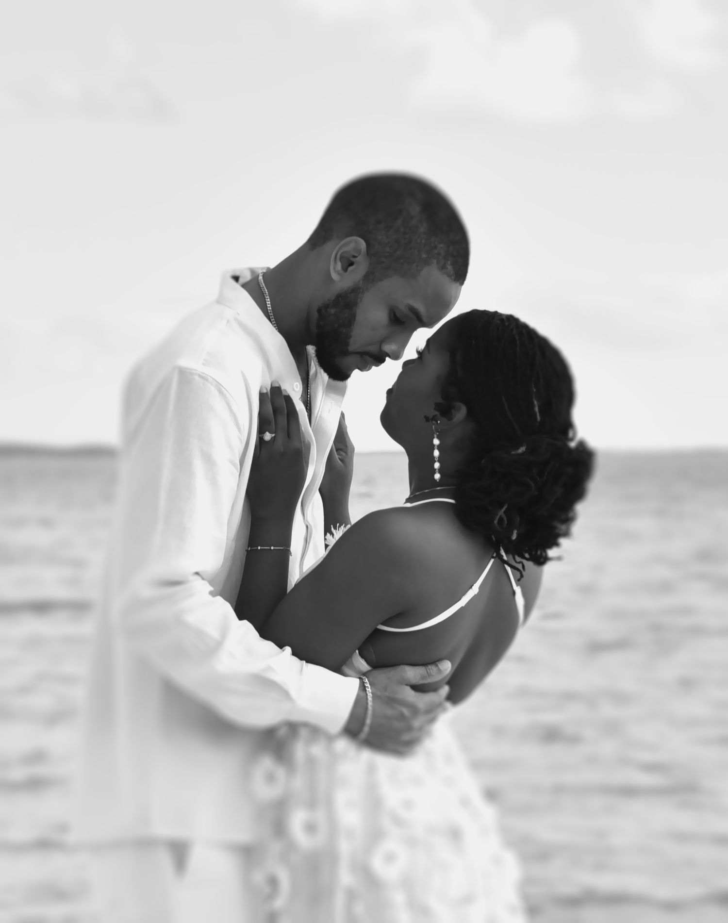 A romantic couple embraces on a beach in black and white, creating a series of intimate seaside moments.