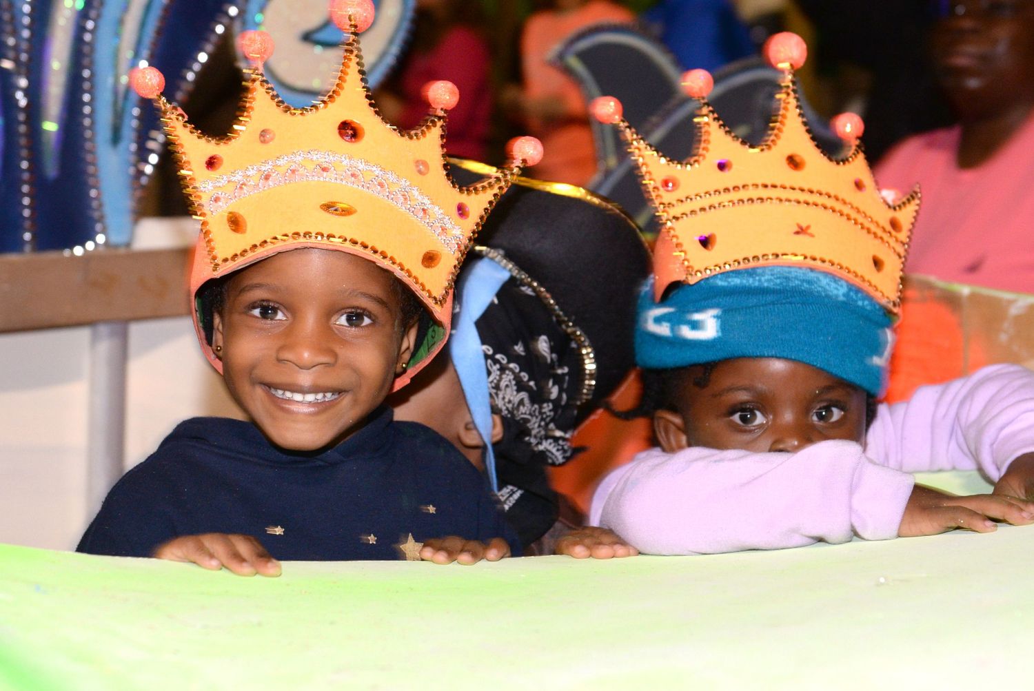 Young birthday celebrants wearing golden crowns participating in a festive event.