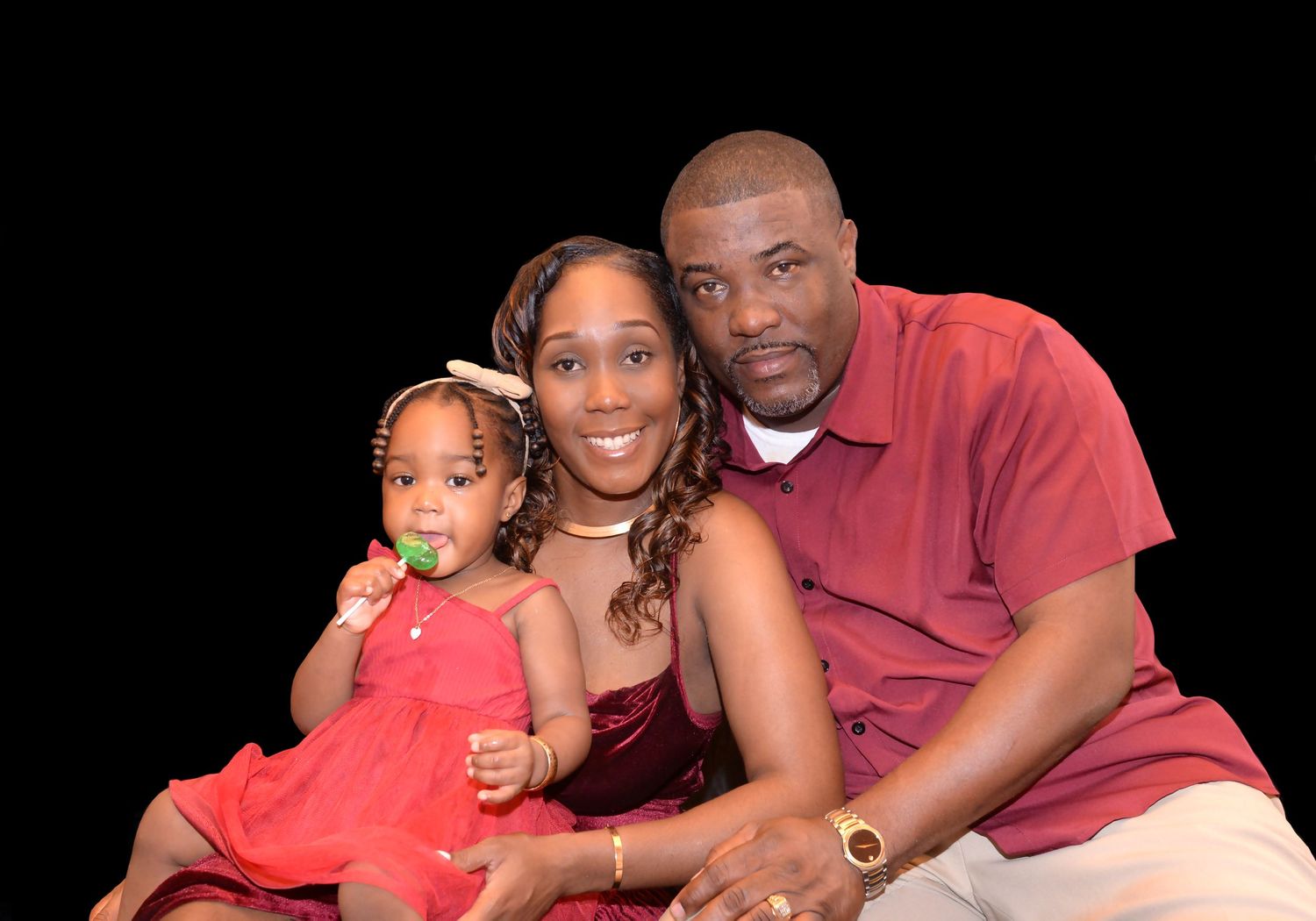 A studio family portrait with coordinated outfits against a black background.