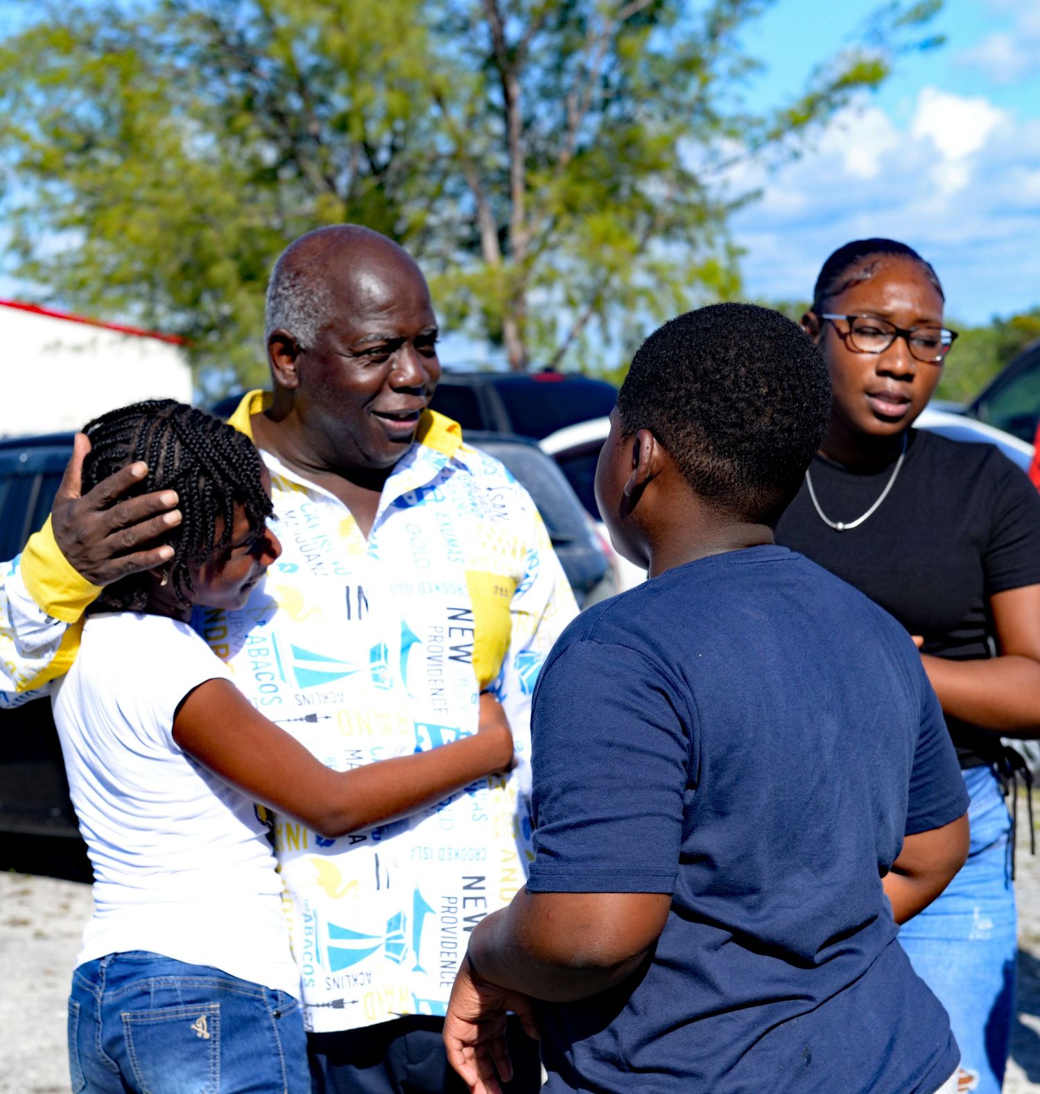 A group of people having an animated conversation outdoors on a sunny day.