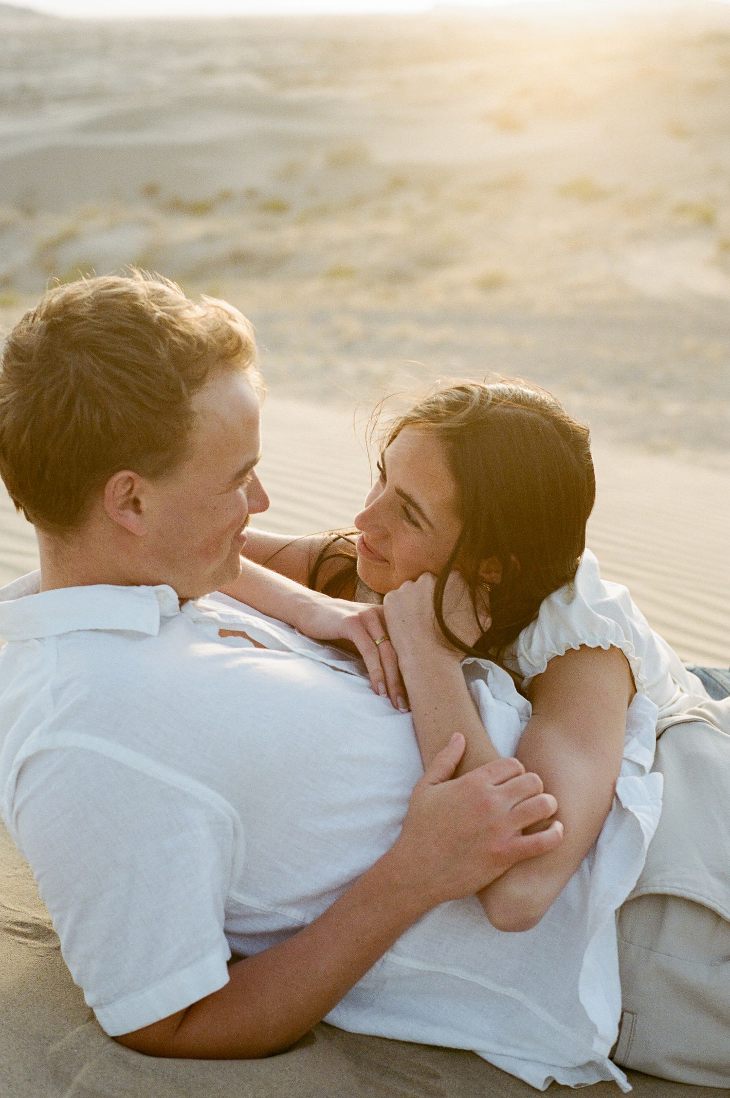 Romantic couple embracing on sandy desert dunes at golden sunset light at Little Sahara Sand Dunes.
