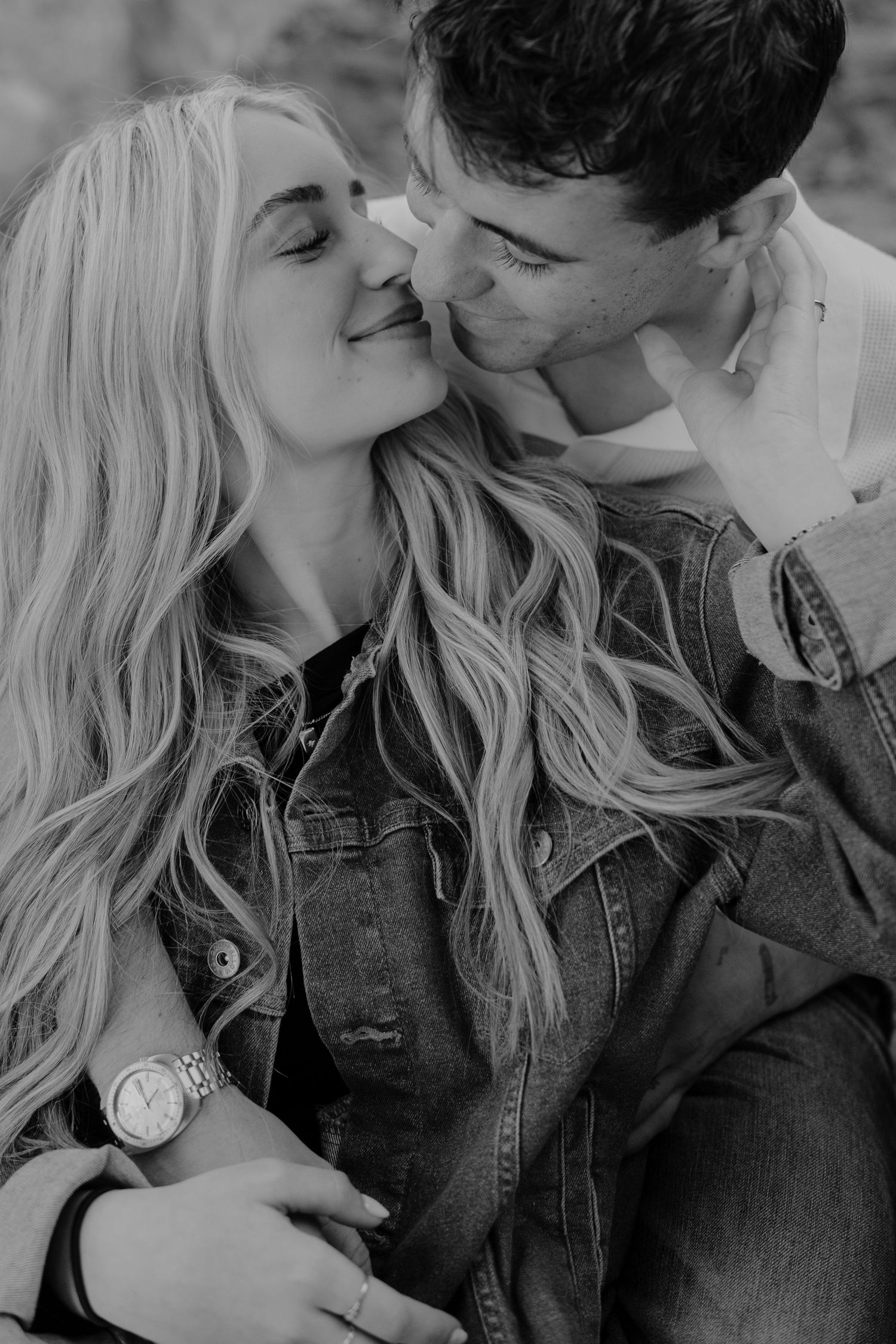 Black and white close-up of a couple sharing a tender kiss outdoors during an engagement session.