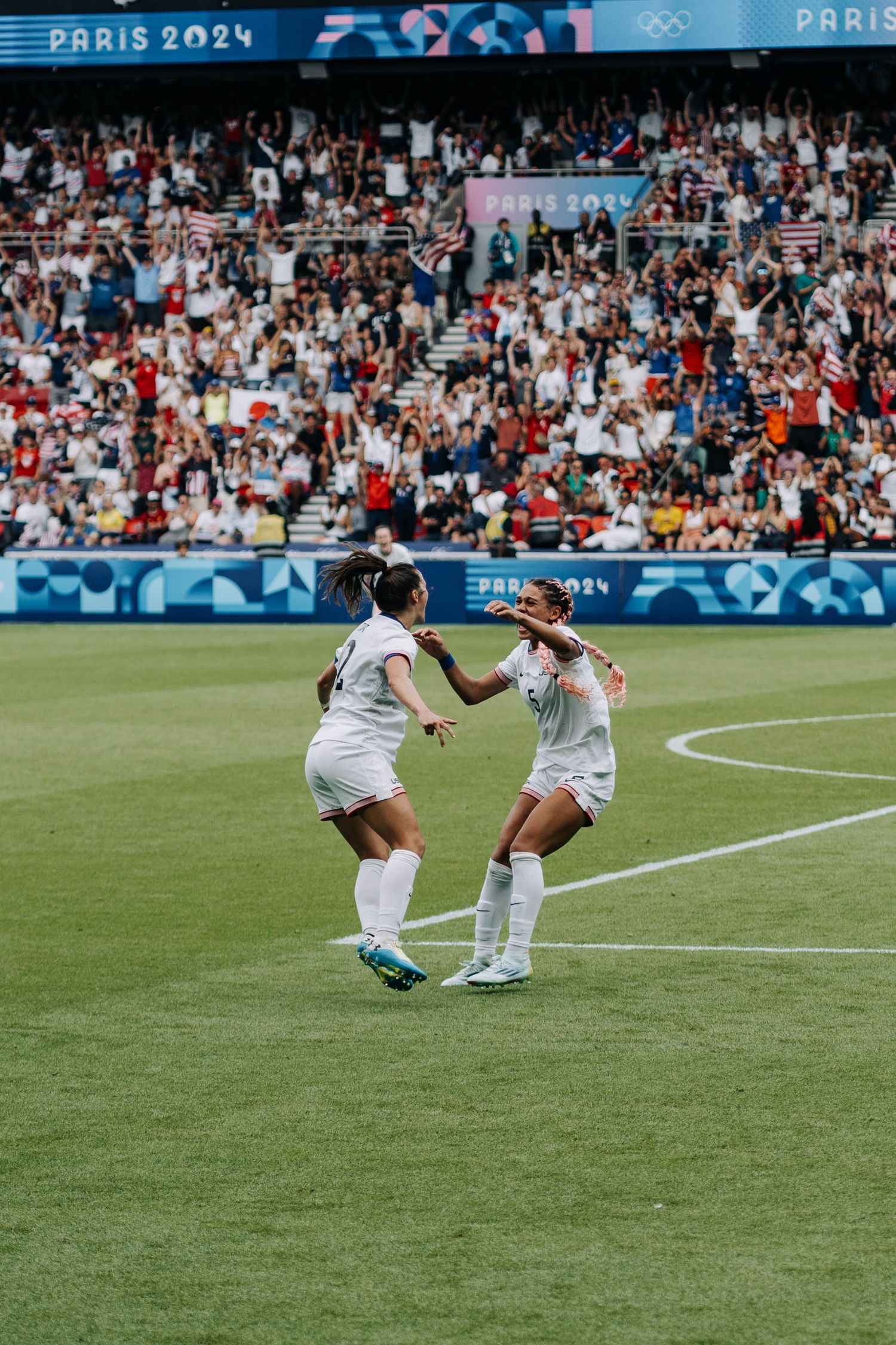 Two female soccer players celebrate a goal together during the Paris 2024 Olympic Games.