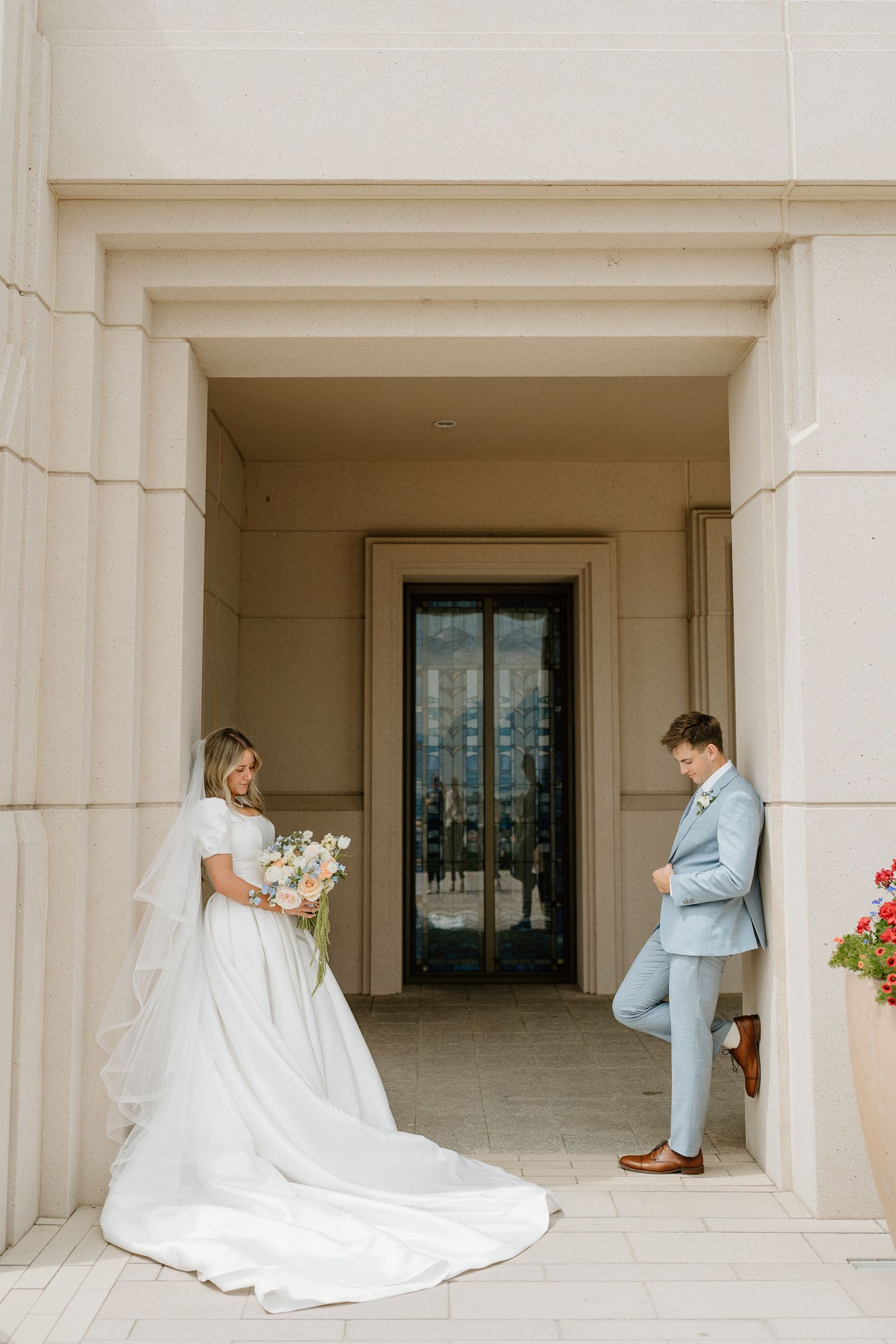 Bride and groom share a quiet moment in elegant temple archway, bride holding floral bouquet.