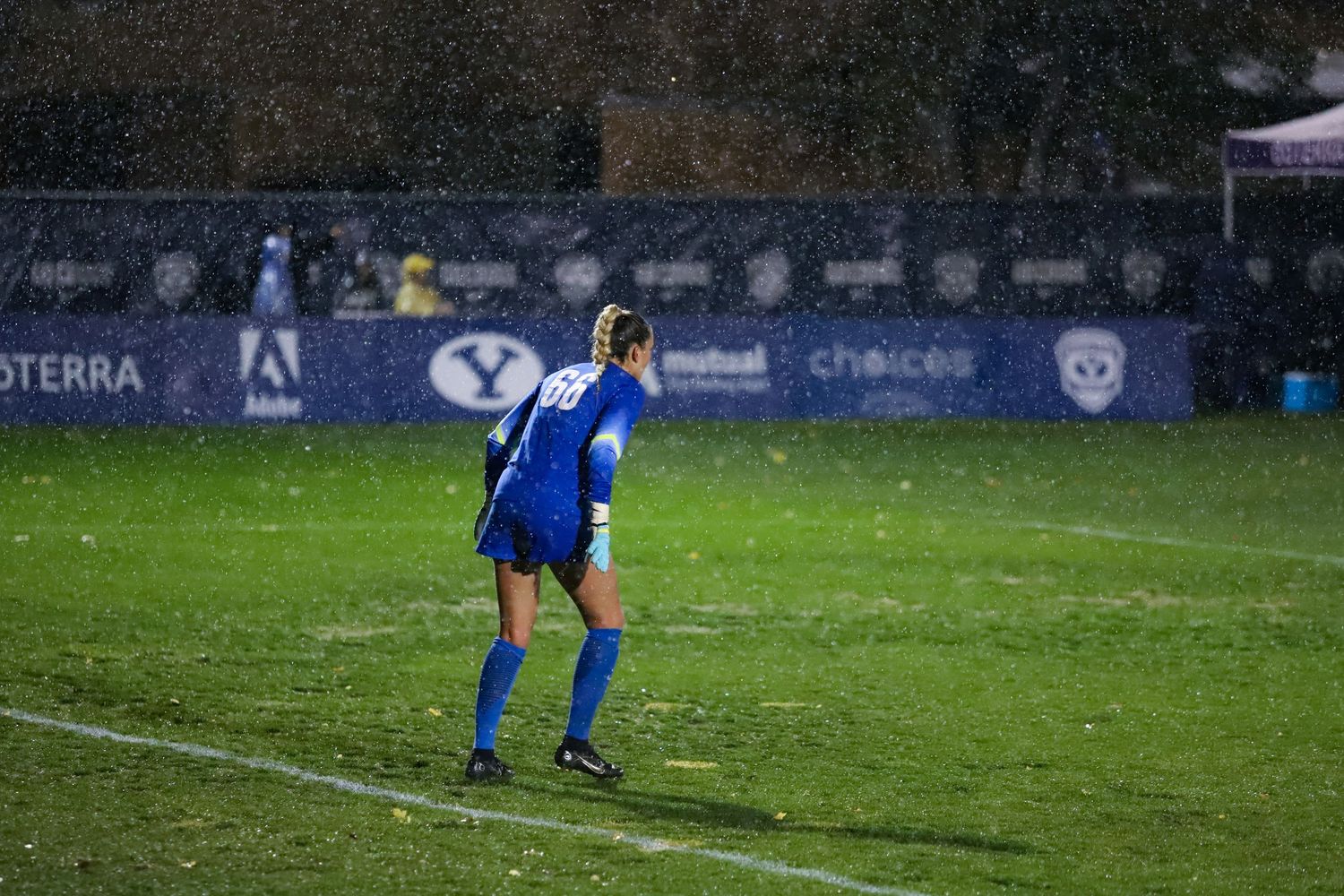 BYU Cougars female soccer goalkeeper standing on a rain-soaked field during a night game.