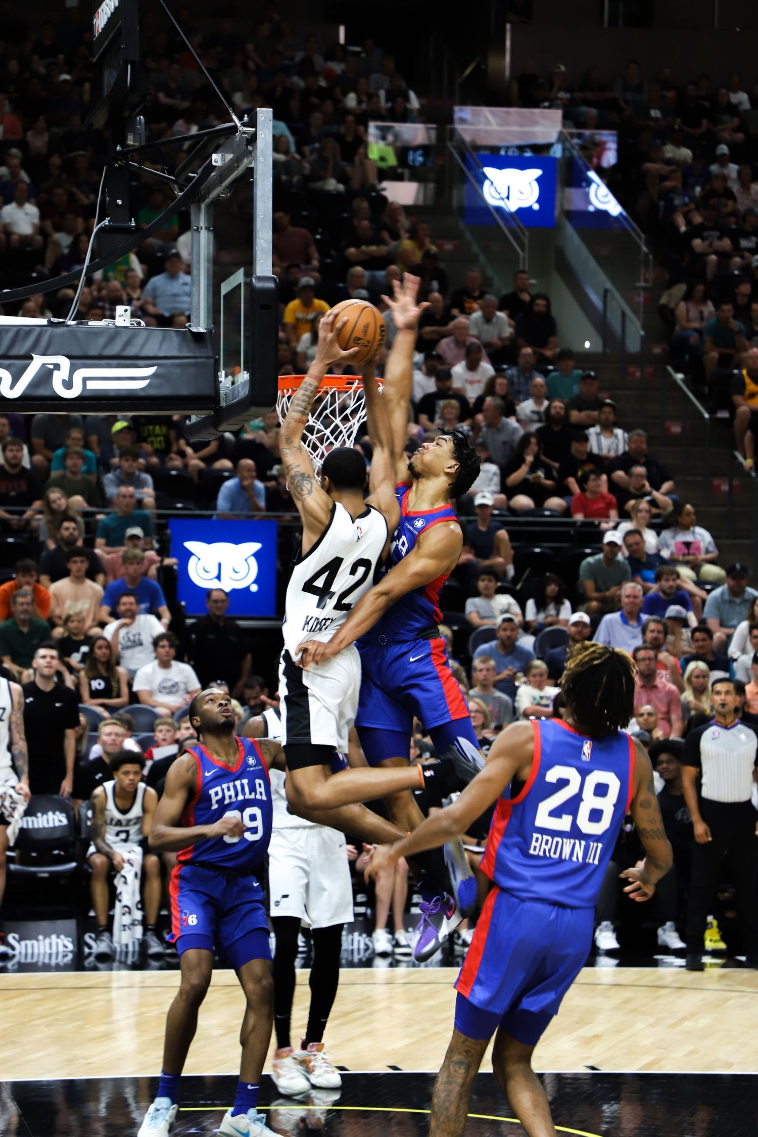 San Antonio Spurs player #42 dunking over Philadelphia 76ers defenders in an NBA Summer League game.