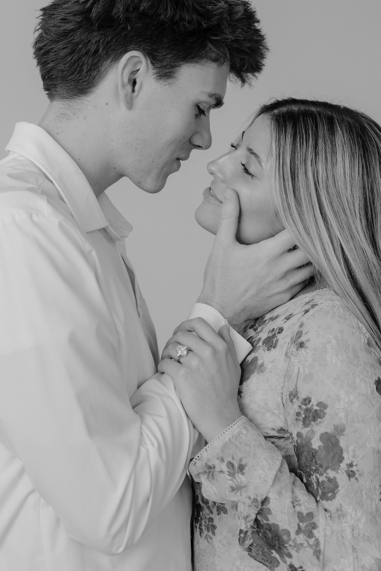 Black and white romantic couple portrait with foreheads touching, woman showing engagement ring at Studio Elevn in Salt Lake City, Utah.