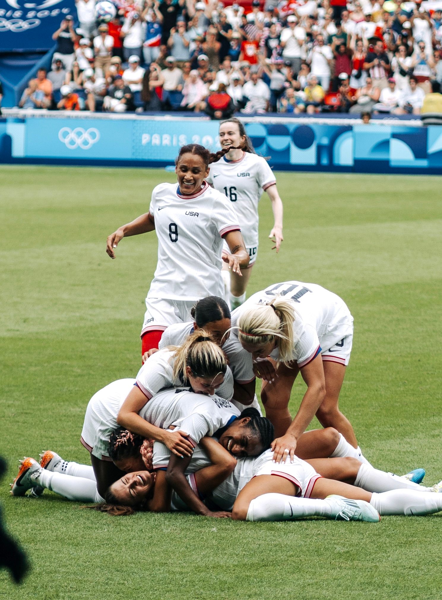US women's soccer team celebrates a goal in a jubilant team huddle at Paris 2024 Olympics.