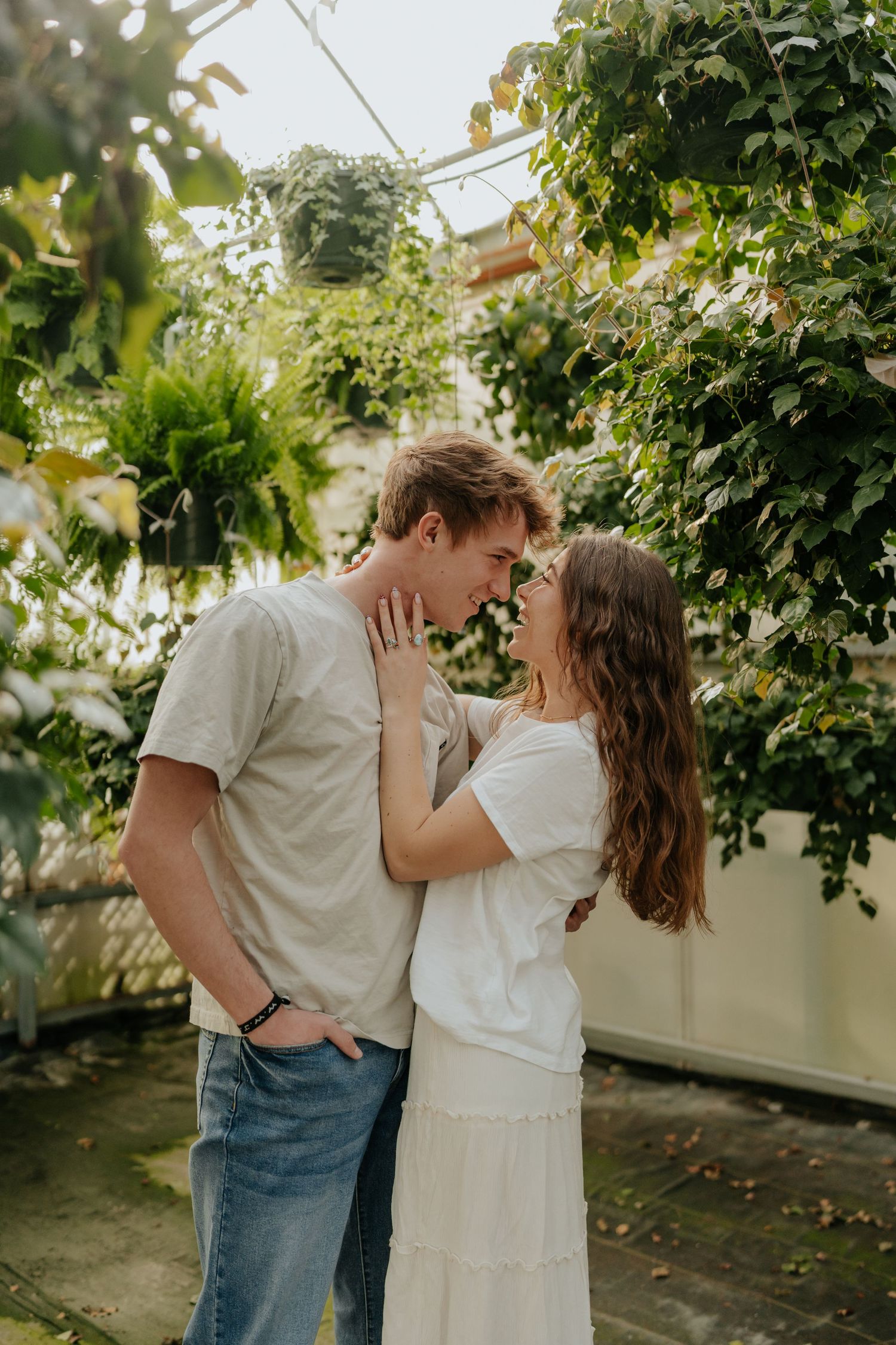 Couple sharing a romantic moment in a lush greenhouse surrounded by tropical green plants in Provo, Utah.