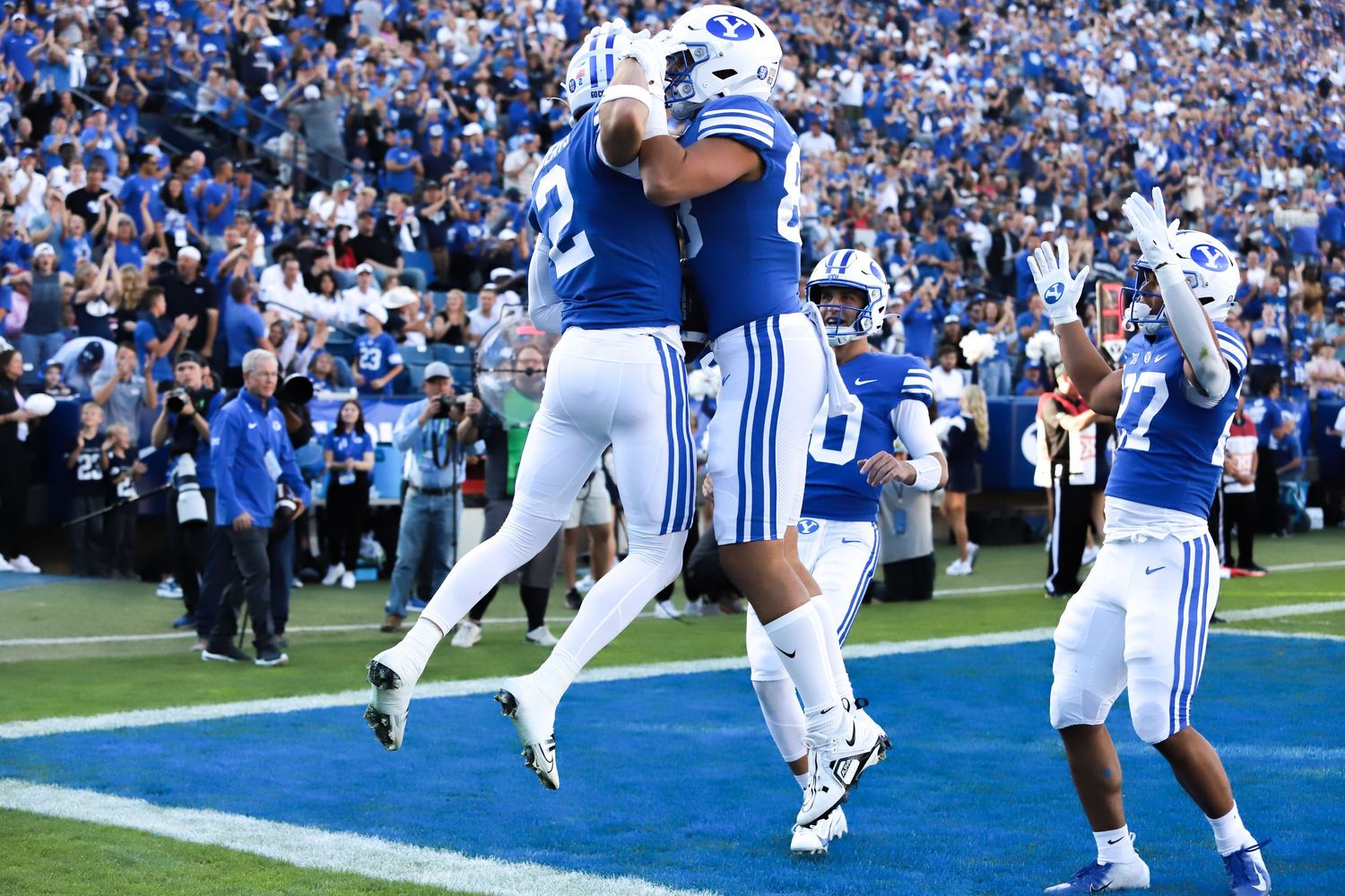 BYU Cougars football players celebrating a touchdown in blue uniforms at LaVell Edwards Stadium.