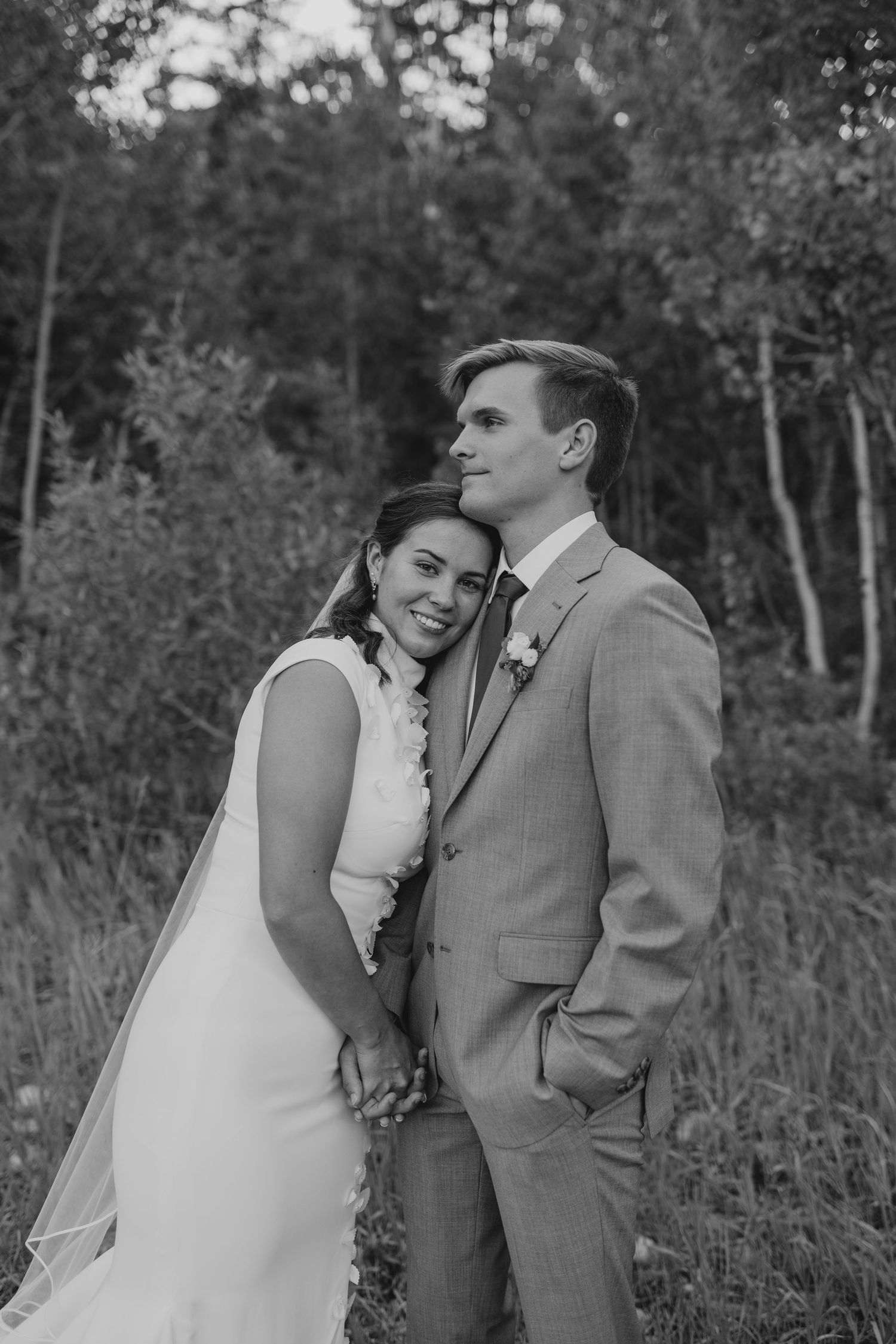 Black and white photo of bride and groom embracing in a forest setting near Provo, Utah.