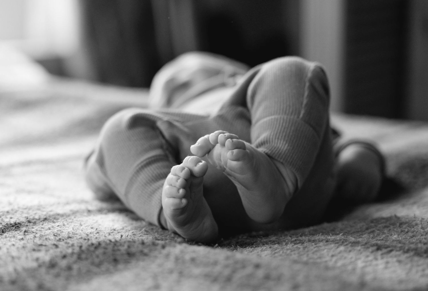 A pair of ballet shoes rests on a textured surface in black and white photography.