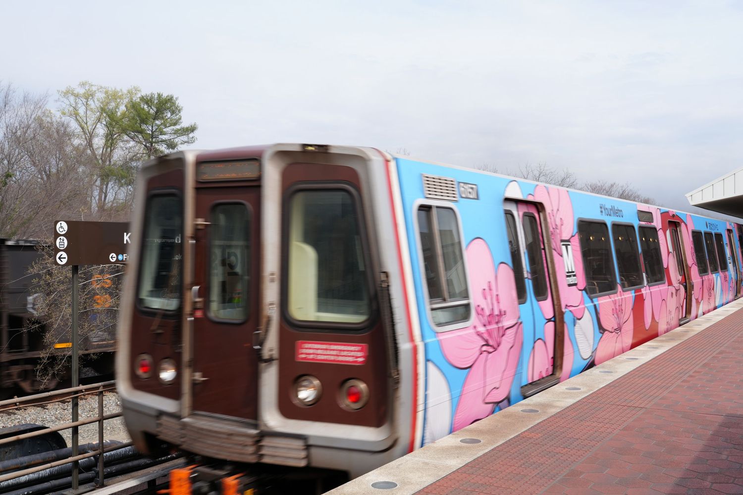 Colorful subway train with pink and blue artistic decorations stopped at a station platform.