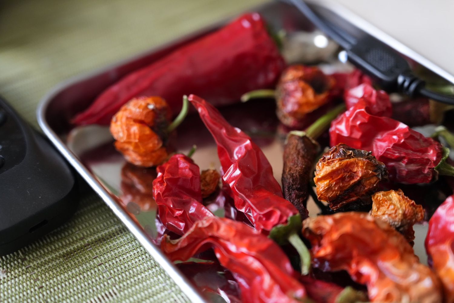 Dried red chili peppers and spices arranged in a metal tray.