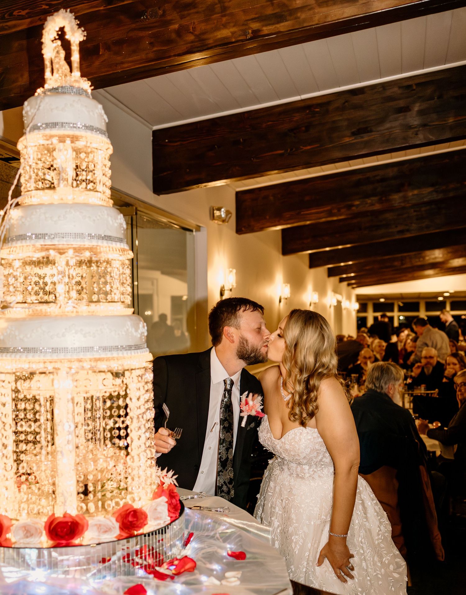 Wedding celebration with elegant crystal chandeliers and guests dancing in a beautifully decorated reception hall.