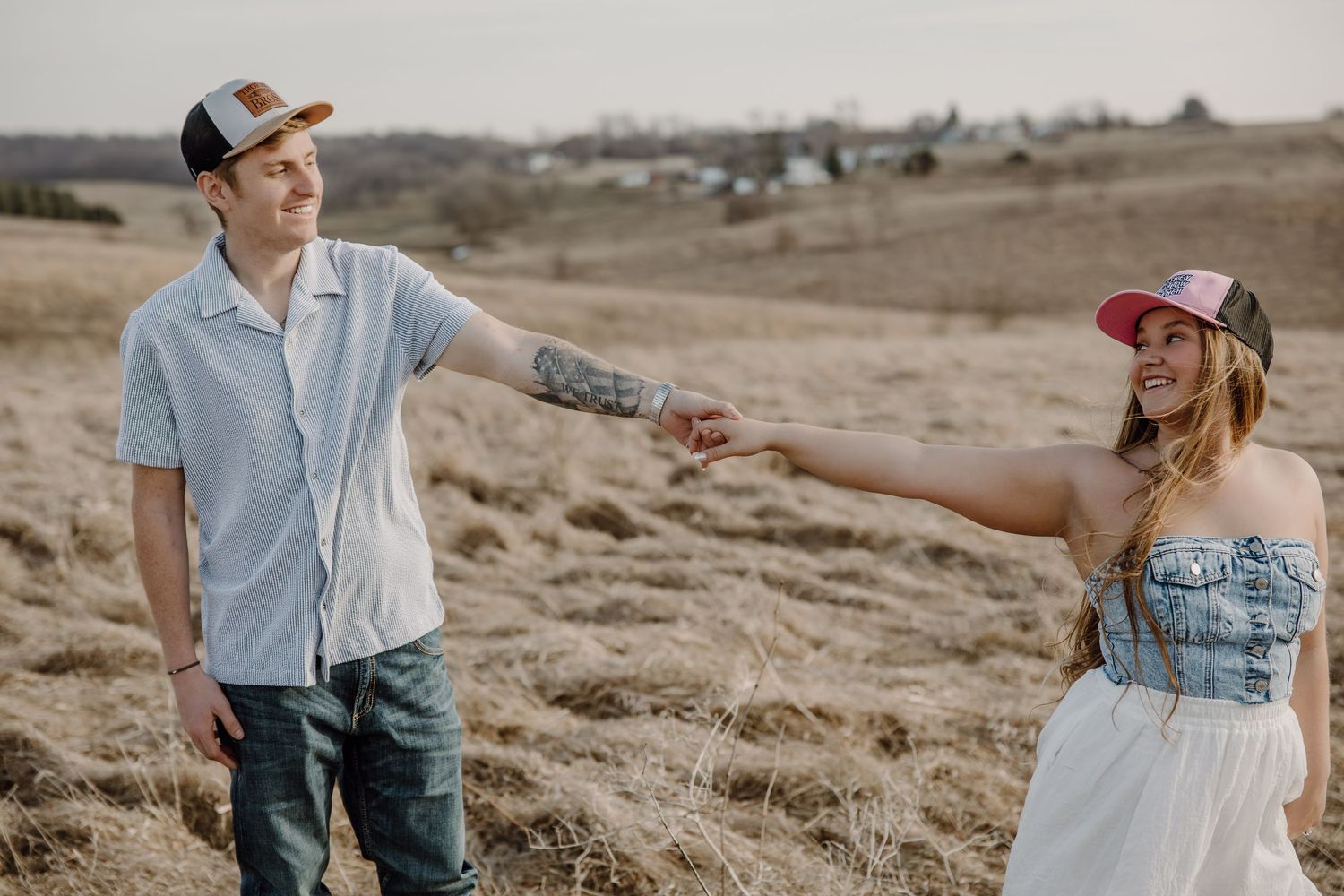A couple walks hand in hand through a desert landscape during a romantic outdoor photo session at sunset.