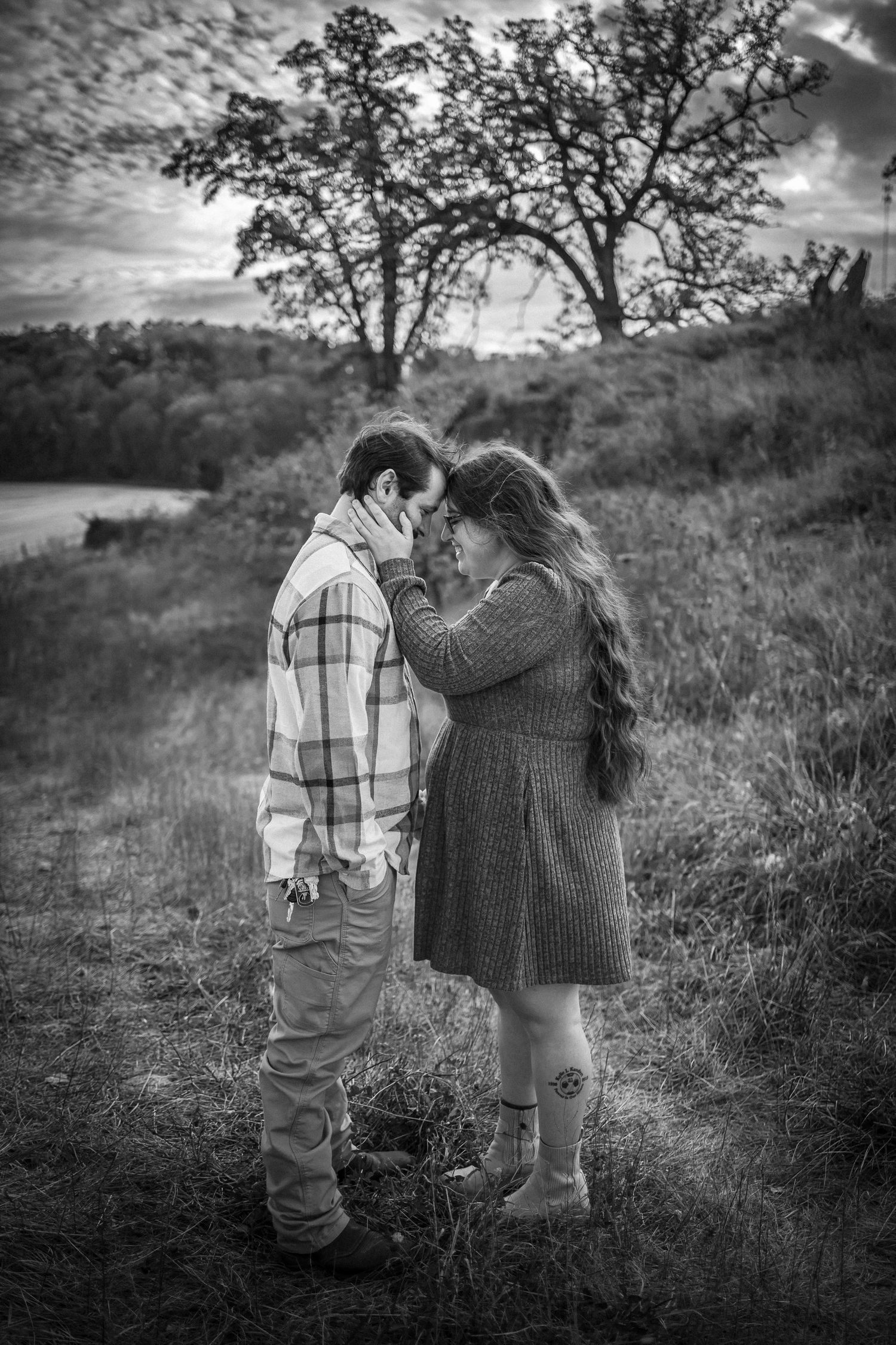 A series of black and white photos showing two children sharing sweet moments together in a grassy field.