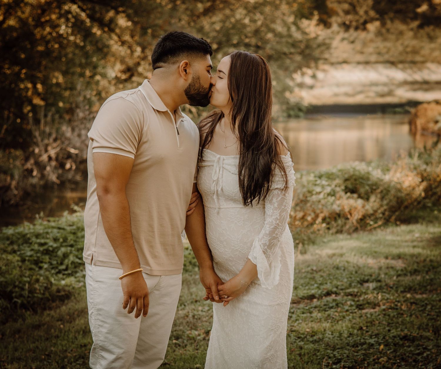 A couple shares an intimate moment in a romantic outdoor setting with warm autumn lighting and natural surroundings.
