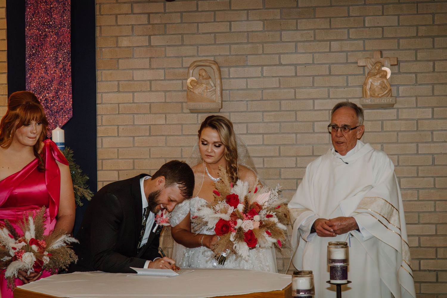 Wedding guests at a reception sign a guestbook and share well wishes at a brick-walled venue.
