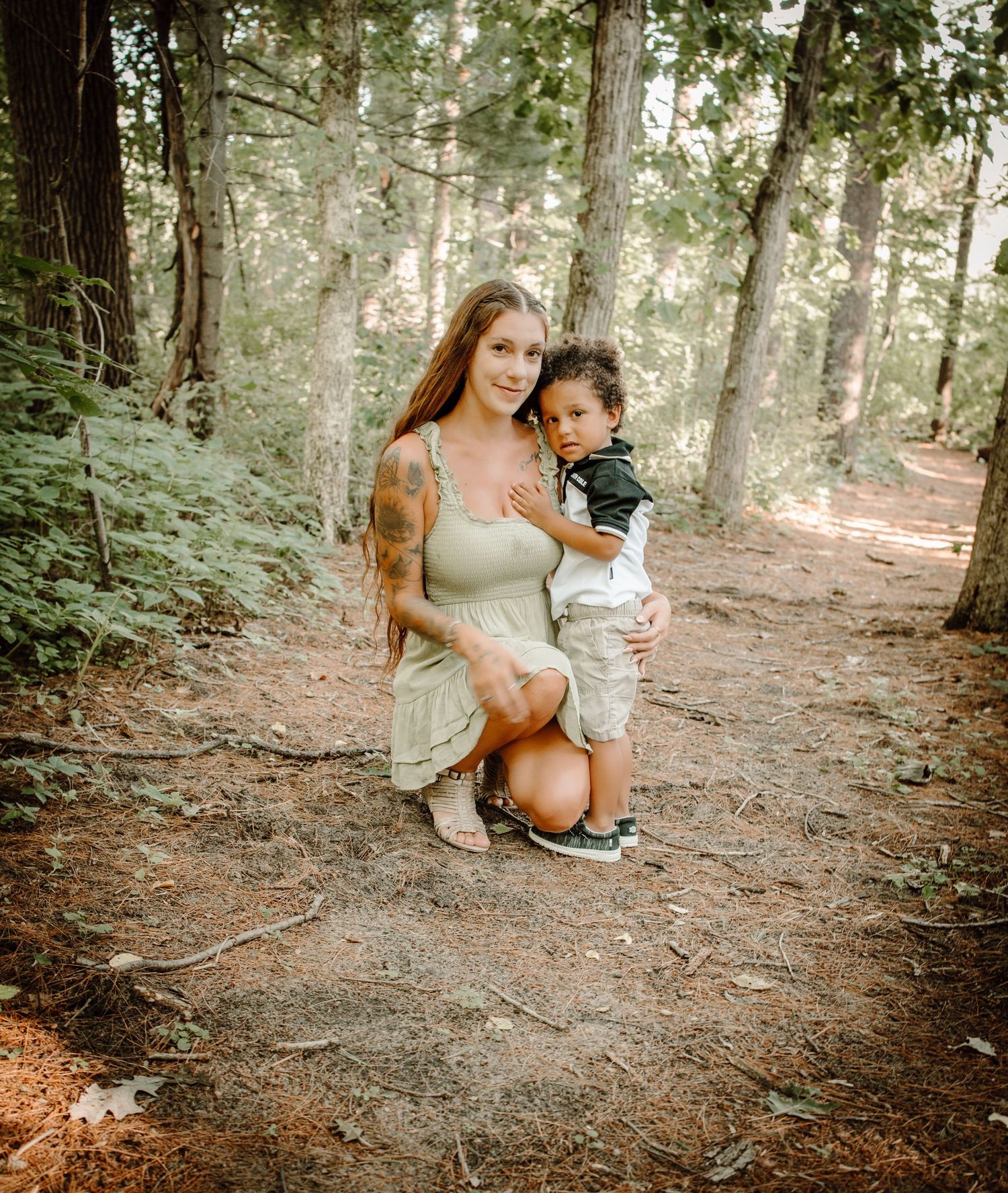 A tender moment captured on a forest trail with sunlight filtering through the trees in a dreamy natural setting.