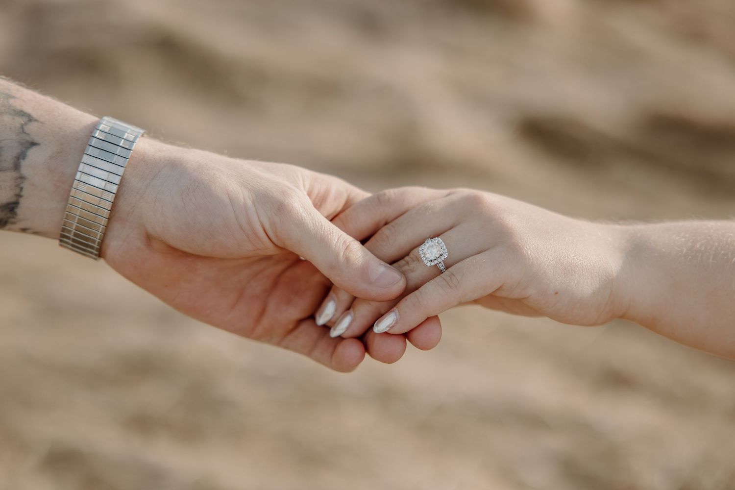 Close-up view of hands exchanging rings during a wedding ceremony on a warm sunny day.