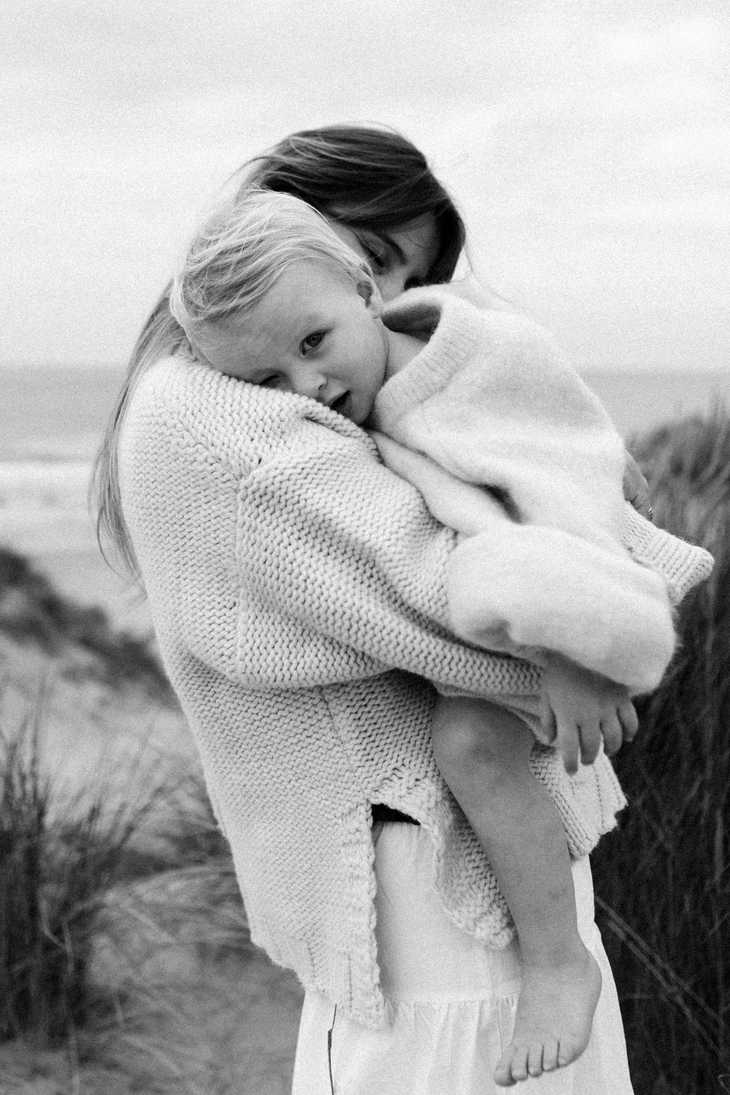 Séance photo famille en extérieur, maman et bébé dans un moment tendre au bord de la mer, photographie naturelle et spontanée.