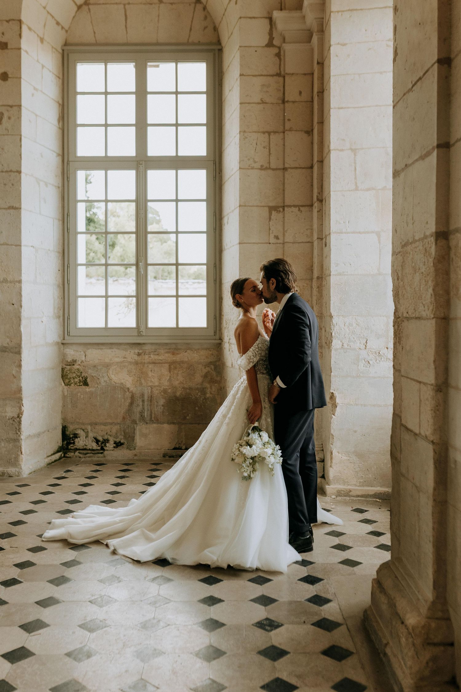 Photographie de mariage dans un lieu historique, couple de mariés dans un moment intime et lumineux.