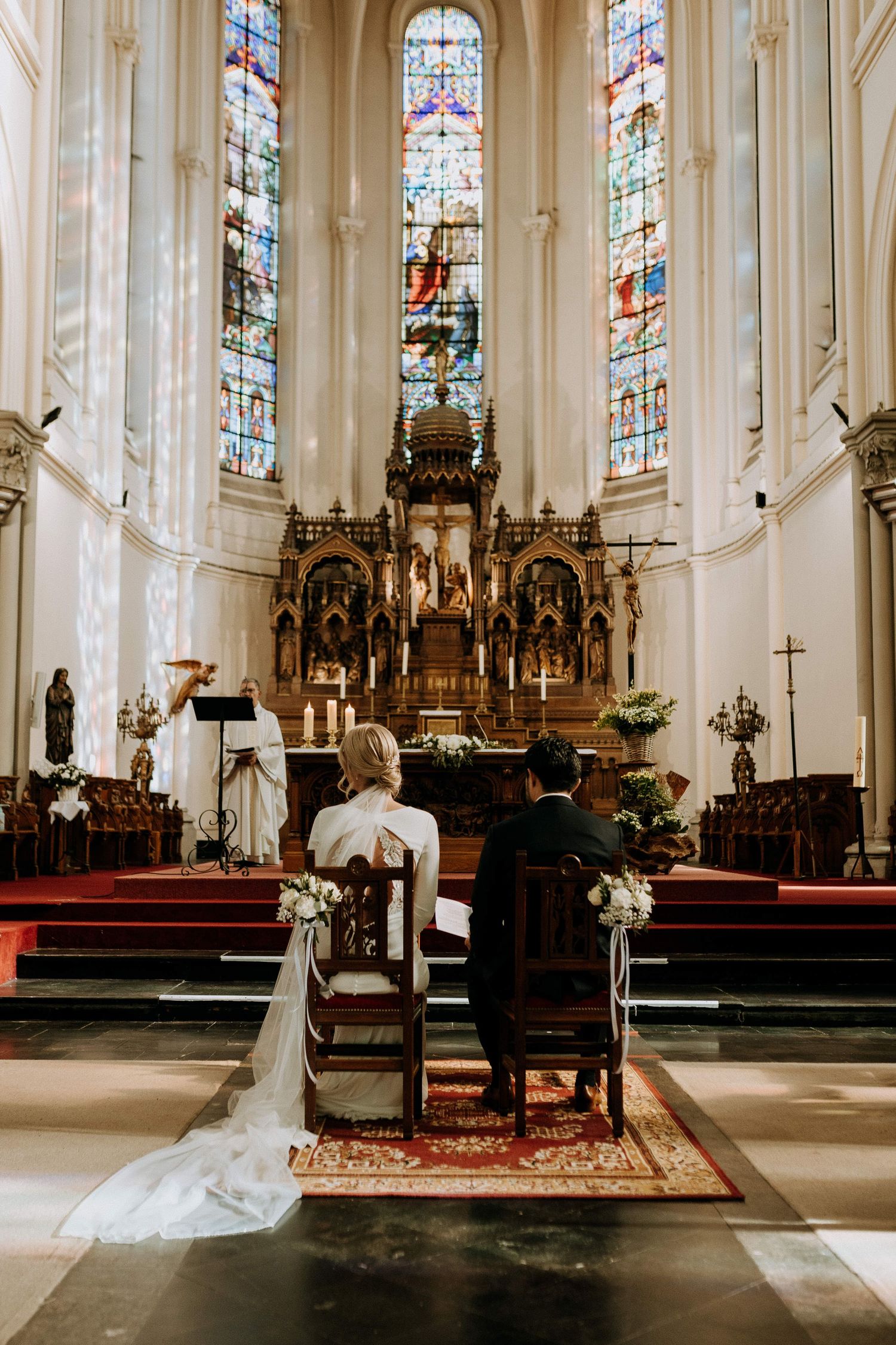 Mariés assis côte à côte pendant une cérémonie religieuse dans une église, atmosphère solennelle et lumineuse.