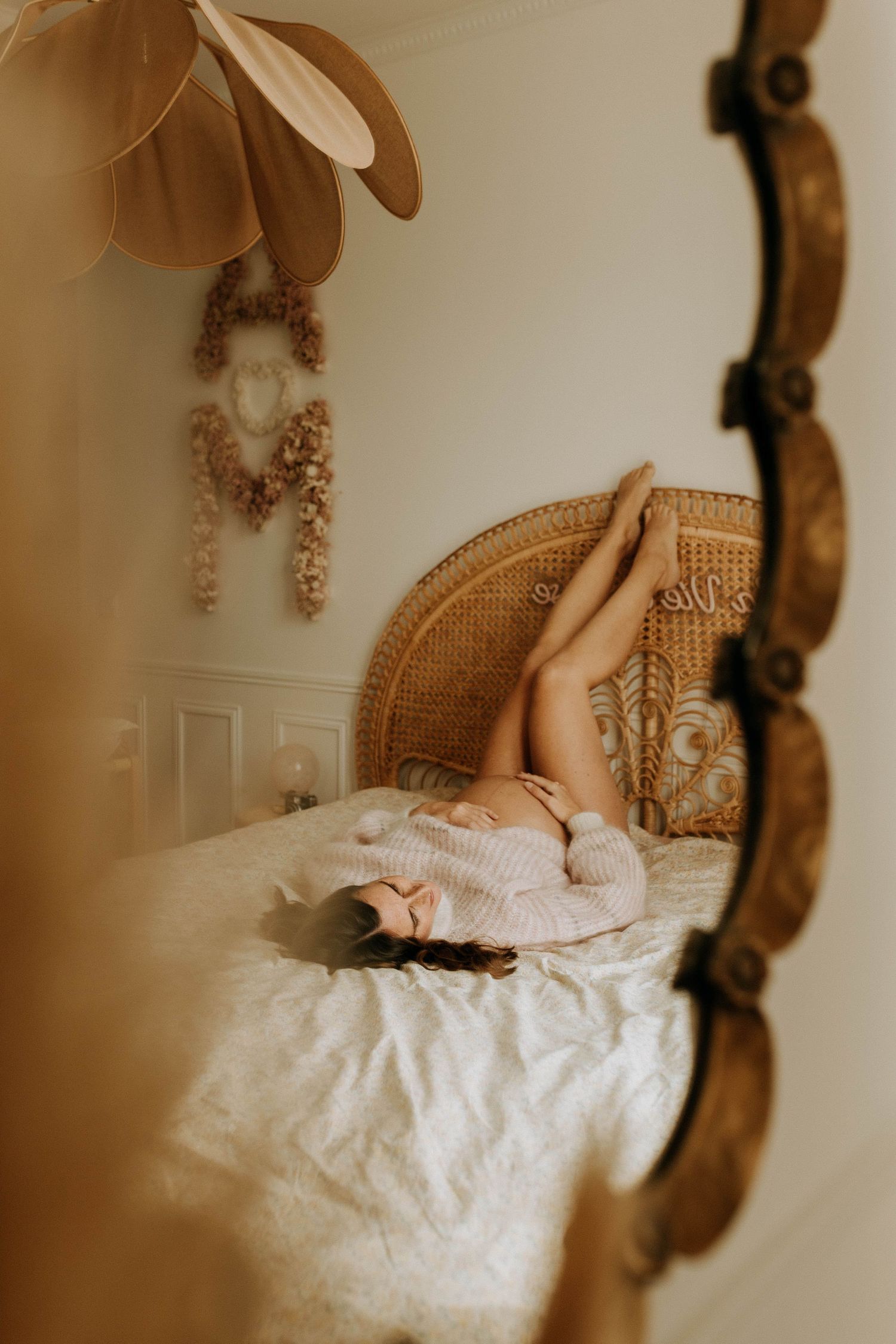 Femme enceinte allongée sur un lit, photographiée à travers un miroir, dans une chambre lumineuse et chaleureuse à Lille, lors d’une séance