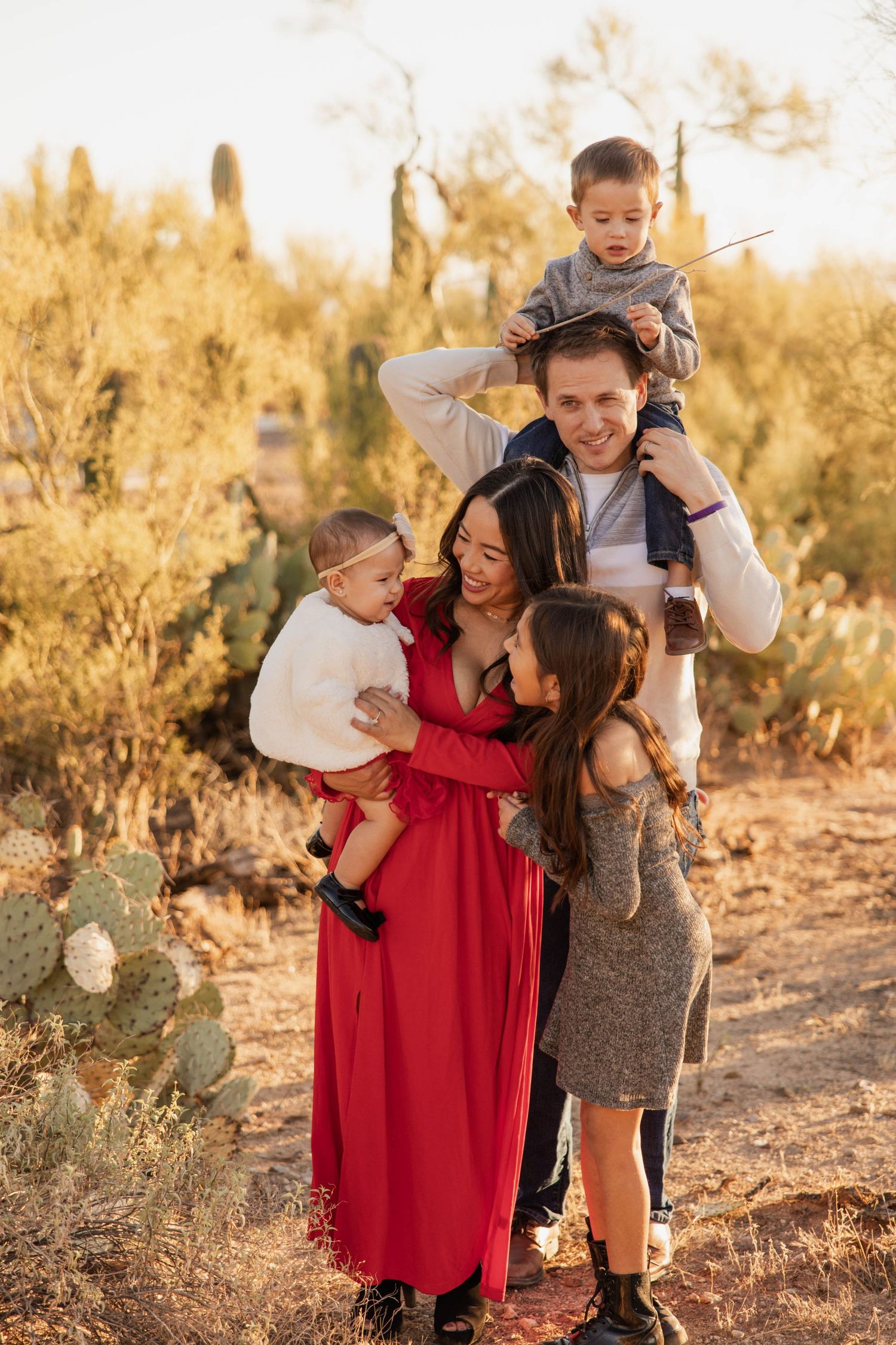 A family shares joyful moments together in a desert landscape during golden hour sunset.