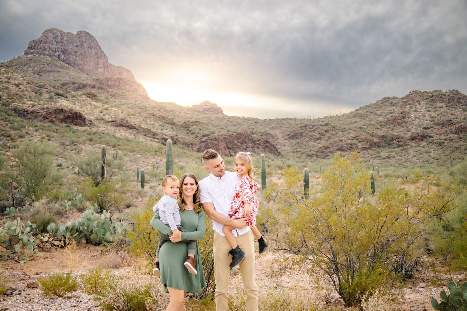 Desert engagement photoshoot in front of mountain peaks at sunset with saguaro cacti and desert landscape.