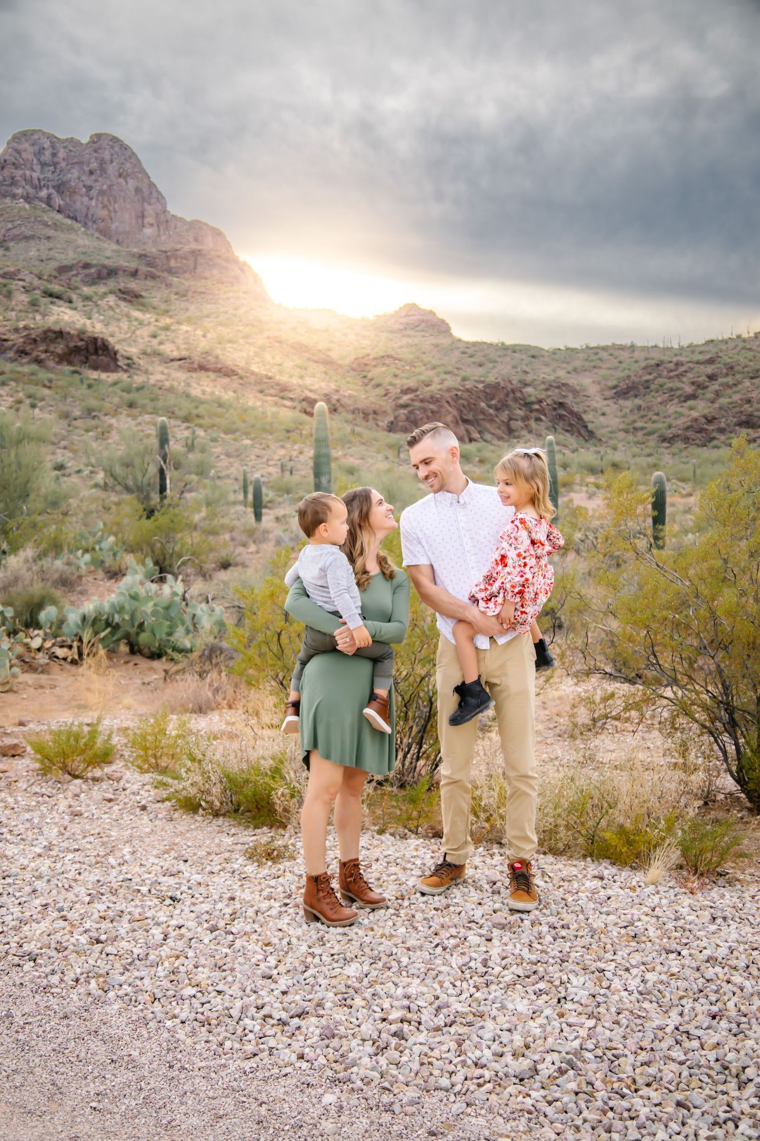 A couple shares romantic moments during a desert engagement photoshoot with dramatic mountain scenery at sunset.