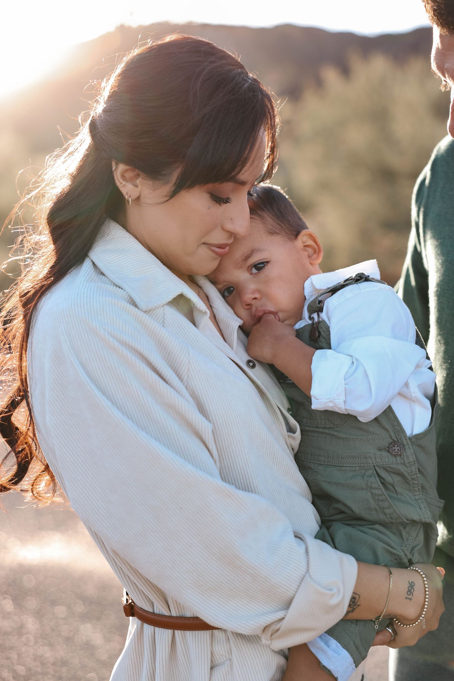 A tender moment between parent and child captured in warm sunlight with a dreamy backlit glow.