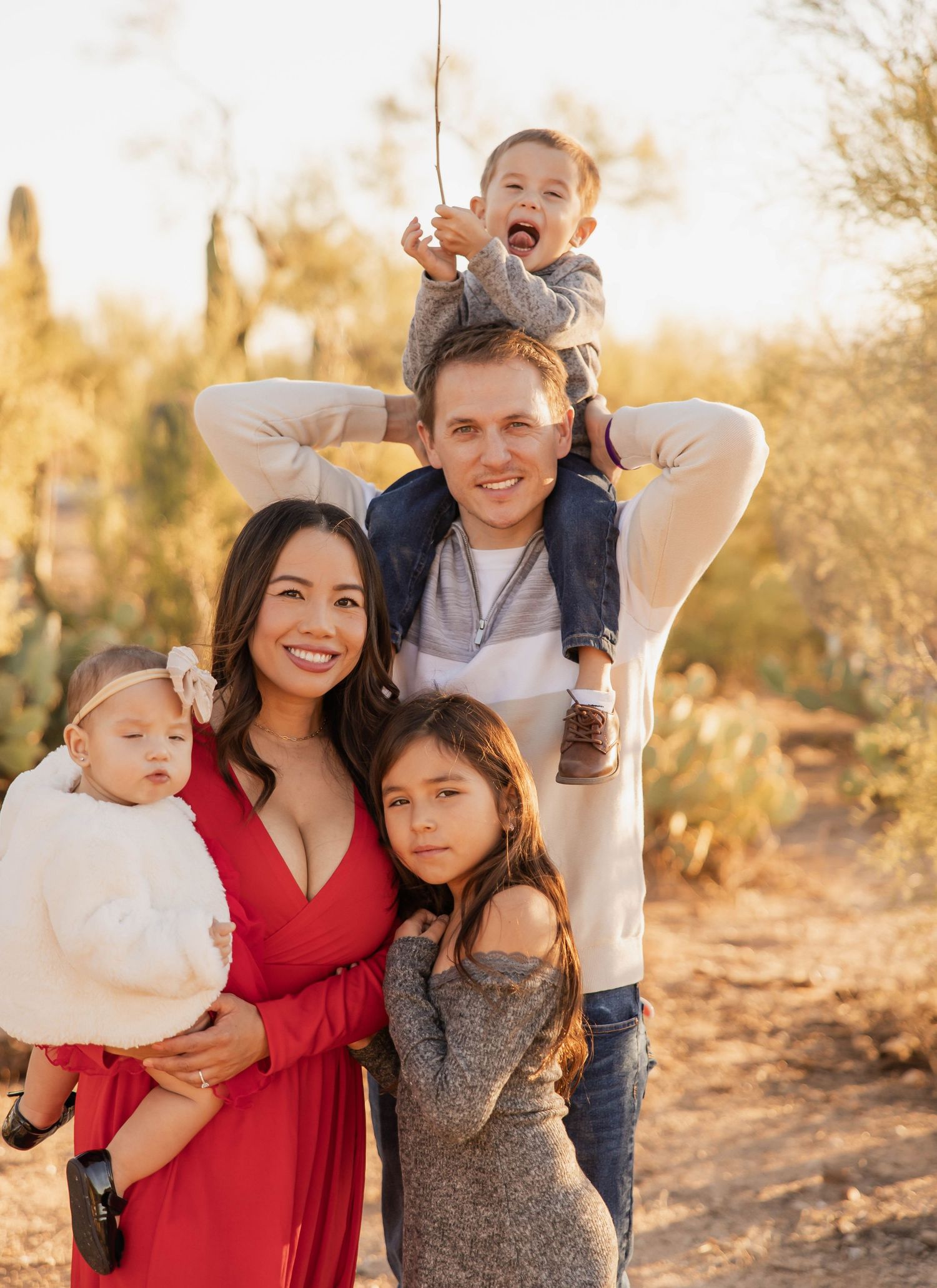 A happy family laughs and plays together during a golden hour photo session in the desert.