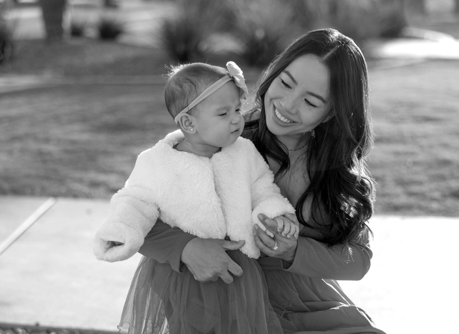 A tender black and white moment of joy and laughter shared between parent and child on a sunny day.