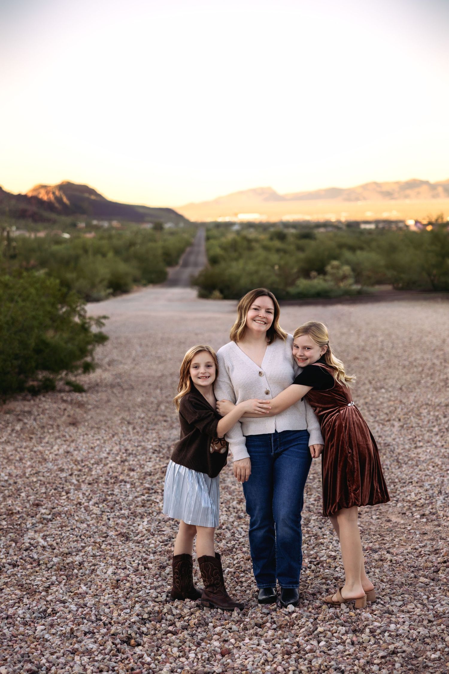 A desert photoshoot at sunset shows people in casual outfits posing together on rocky terrain.