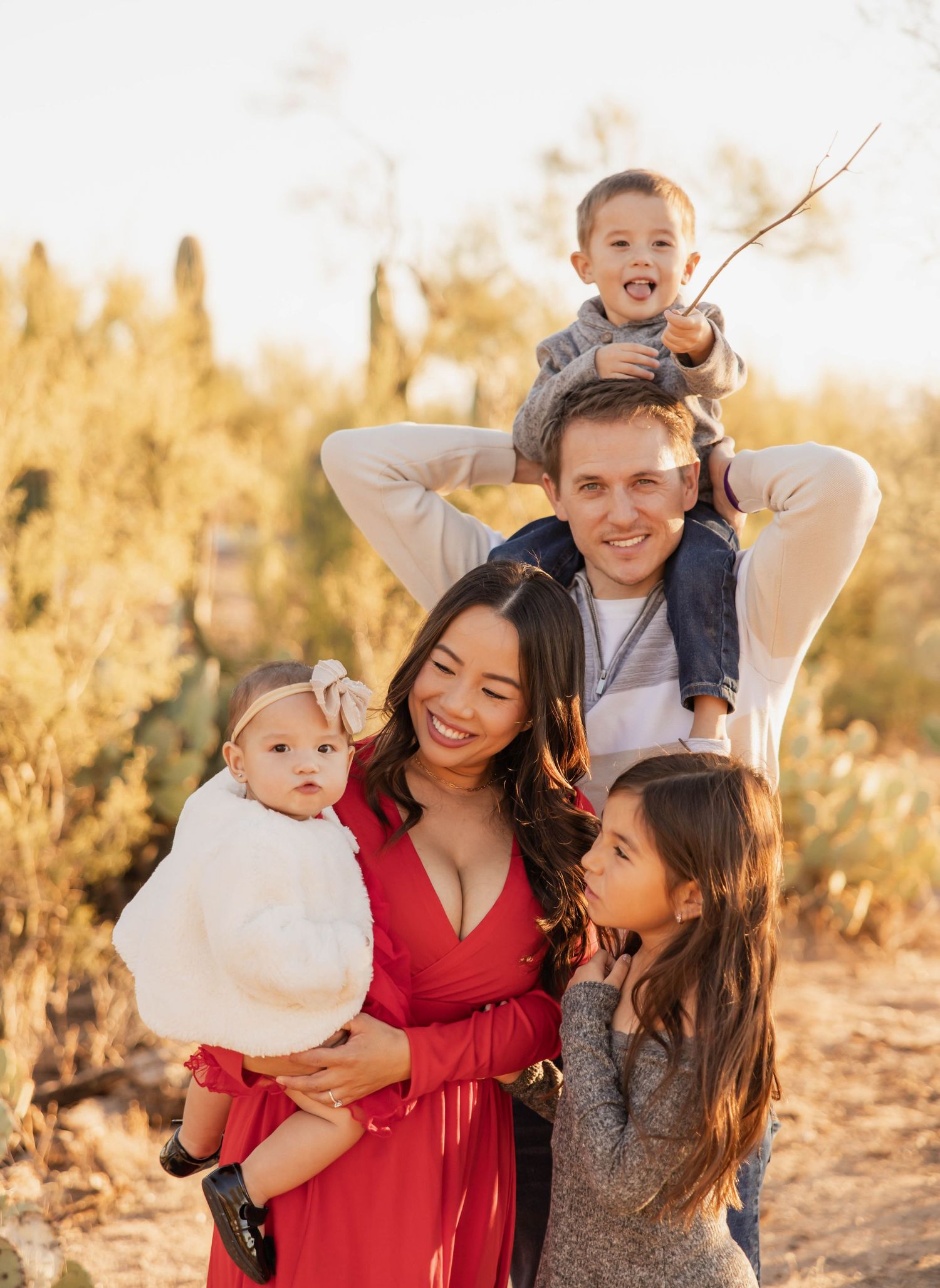 A family shares joyful moments together in a desert setting during golden hour, creating candid and playful portraits.